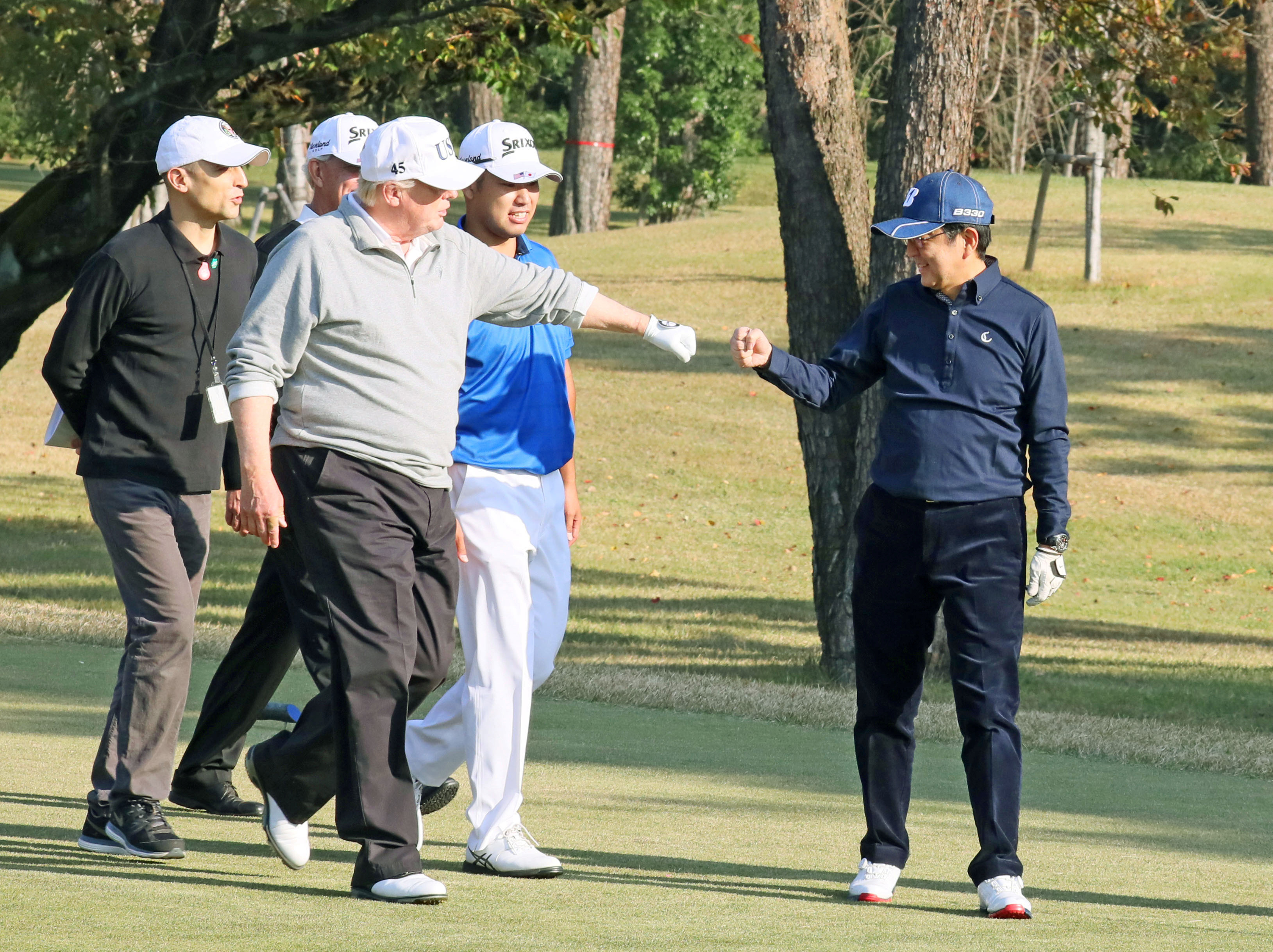 President Donald Trump share a fist bump with Japan's Prime Minister Shinzo Abe as they play golf at the Kasumigaseki Country Club north of Tokyo, Japan on Nov. 5, 2017. (Japan's Cabinet Public Relations Office/Kyodo/via Reuters)