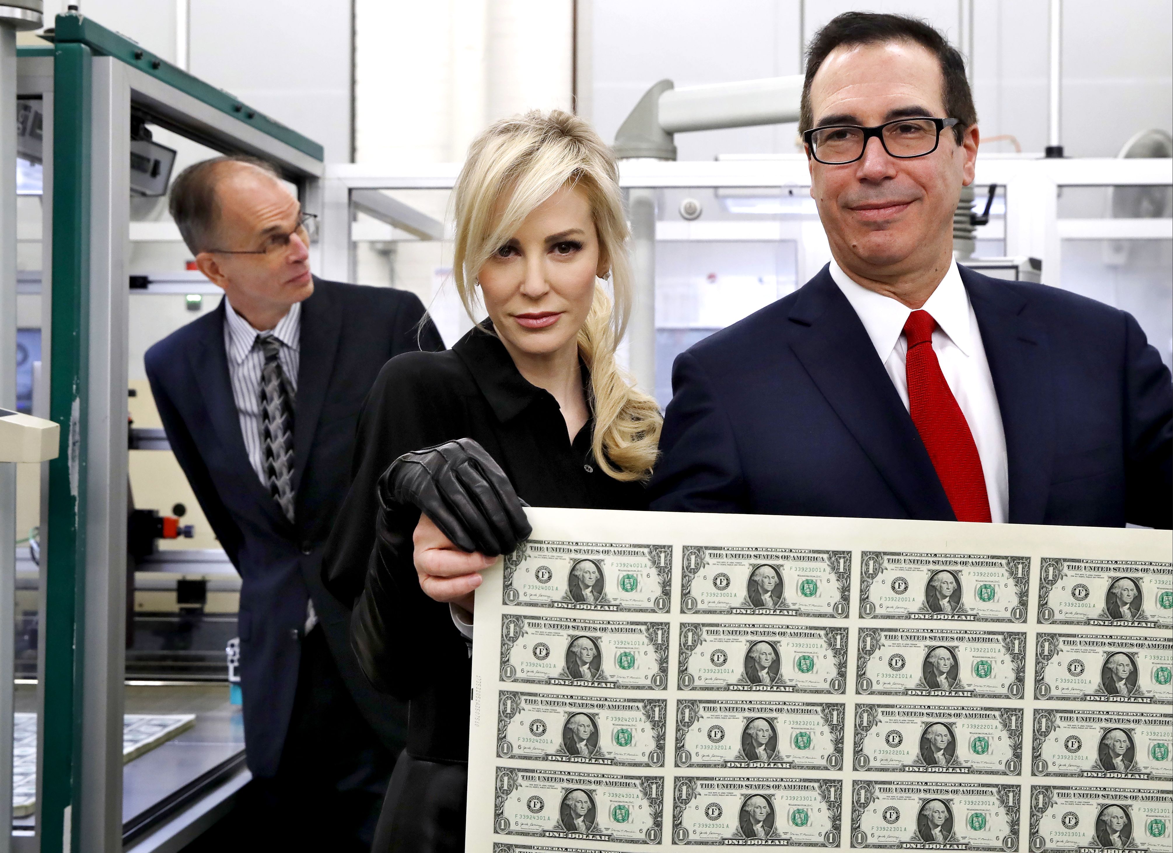 Treasury Secretary Steven Mnuchin, right, and his wife Louise Linton, hold up a sheet of new $1 bills, the first currency notes bearing his and U.S. Treasurer Jovita Carranza's signatures, in Washington on Nov. 15.