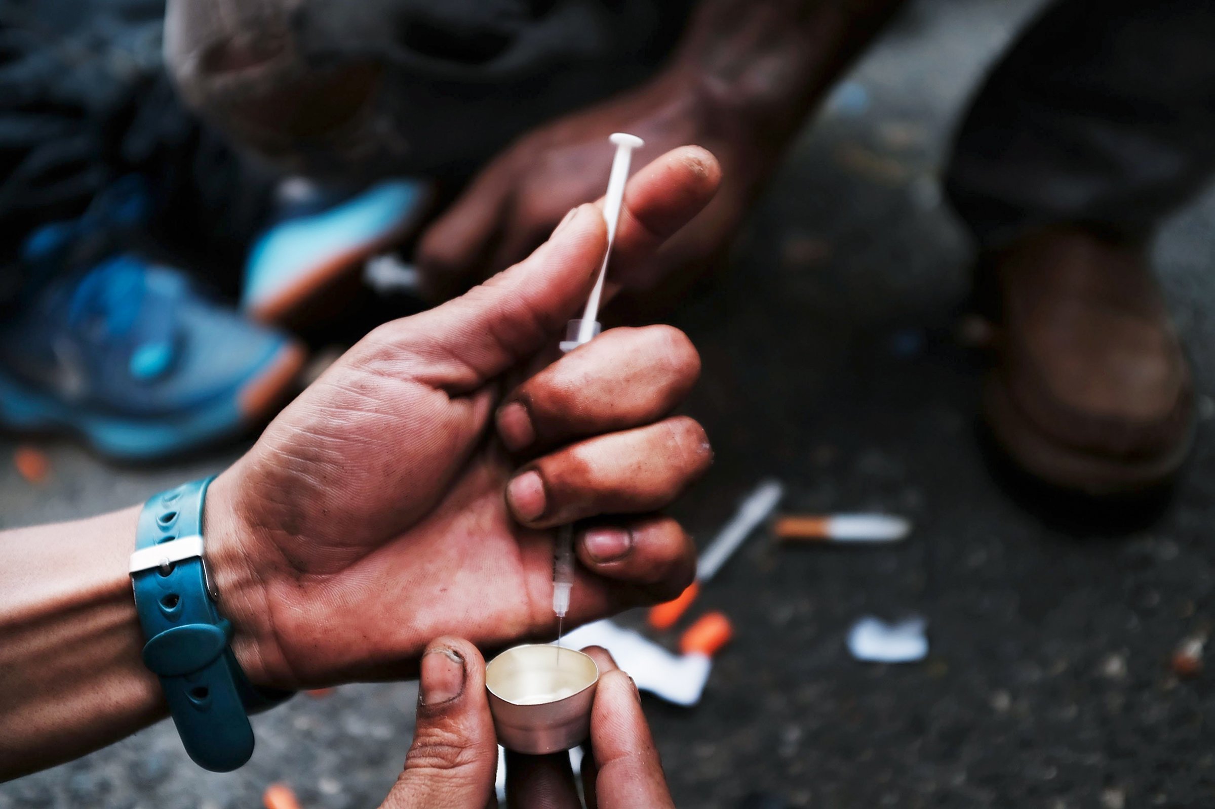 A user prepares to take heroin on a New York City street