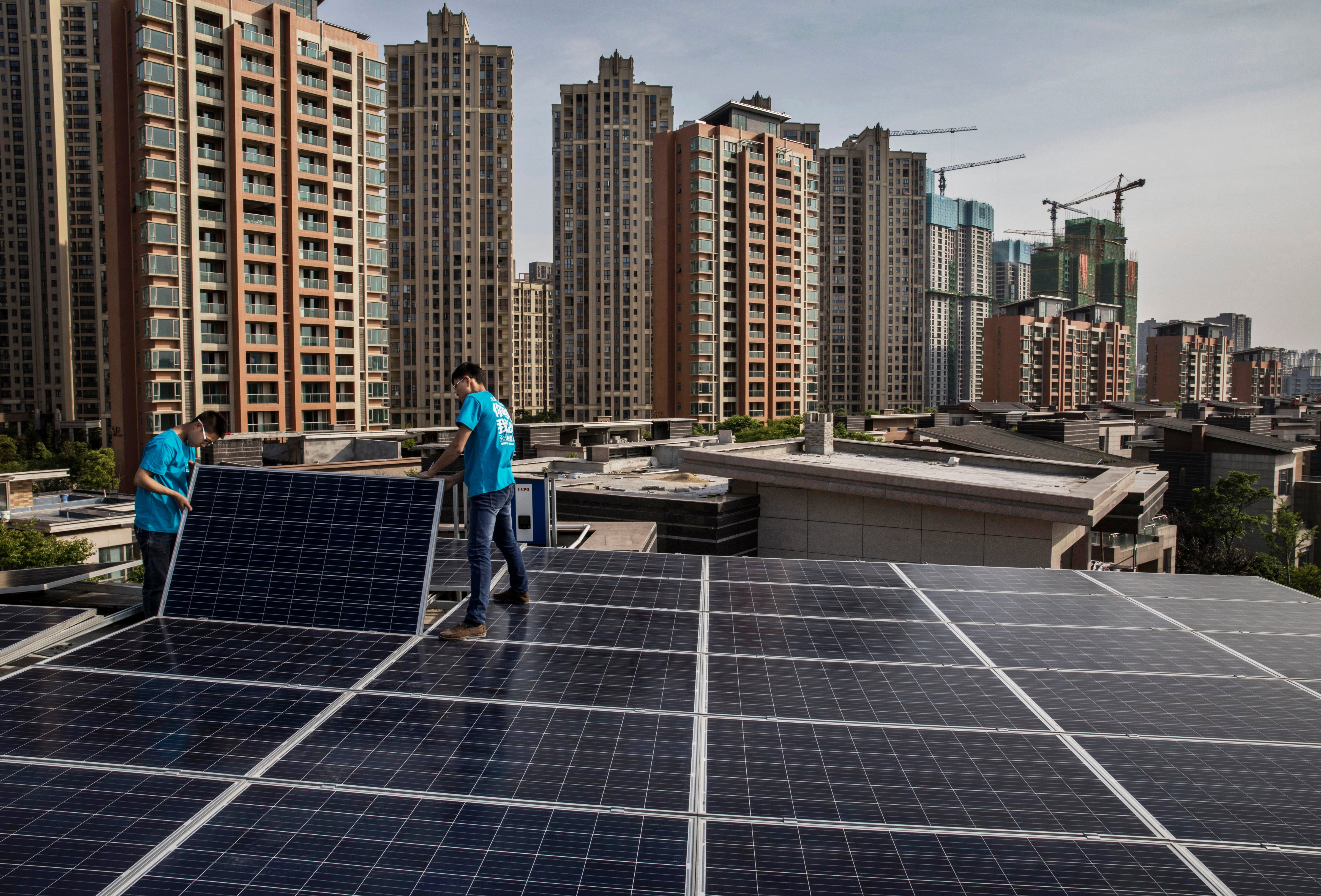Chinese workers from Wuhan Guangsheng Photovoltaic Company install solar panels on the roof of a building on April 27 in Wuhan, China. (Kevin Frayer—Getty Images)