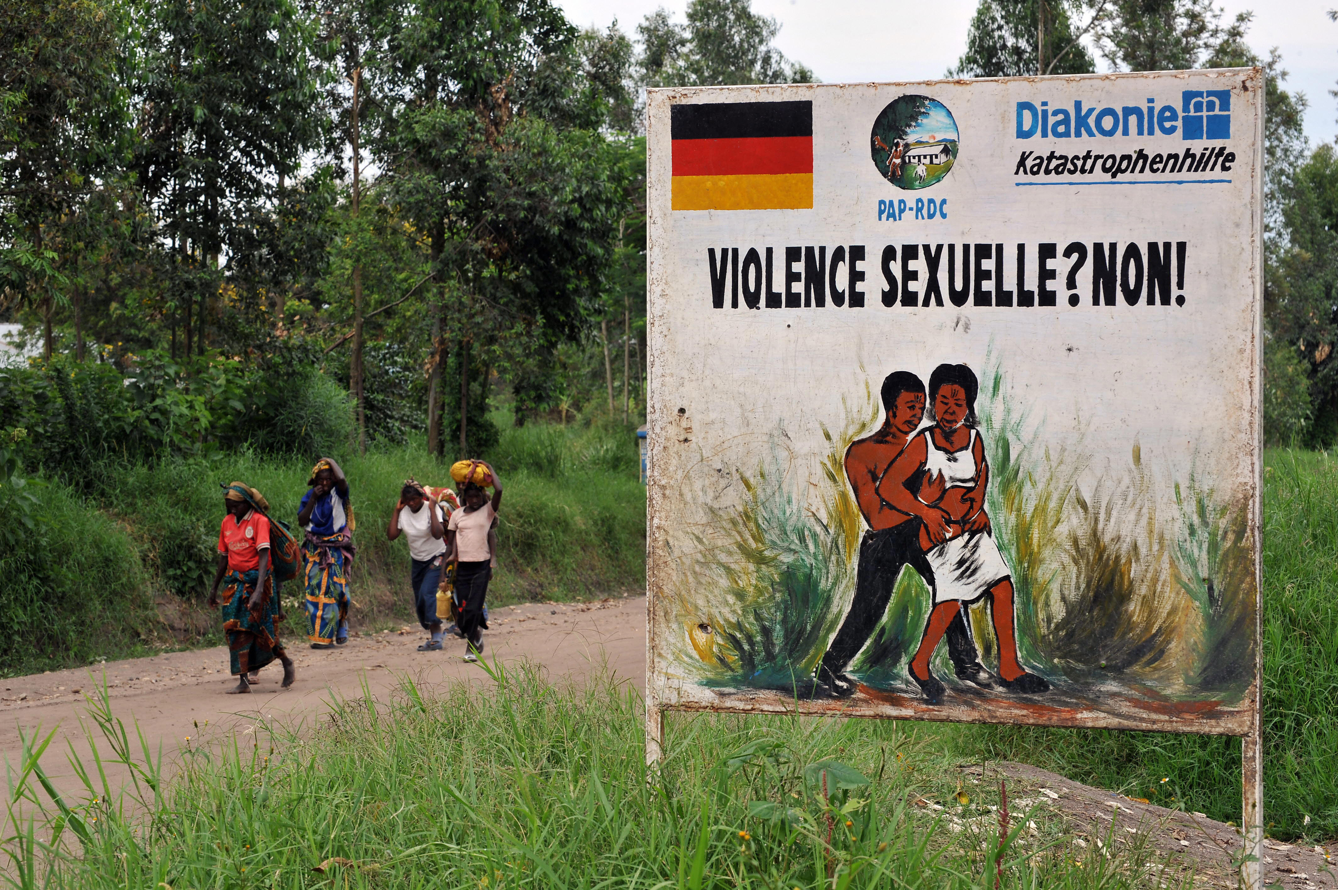 Congolese women walk past a sign opposing sexual violence on Dec.. 4, 2008 in Nyamilima, in Nord-Kivu, in the east of the Democratic Republic of Congo (DRC). (Pascal Guyot—AFP/Getty Images)