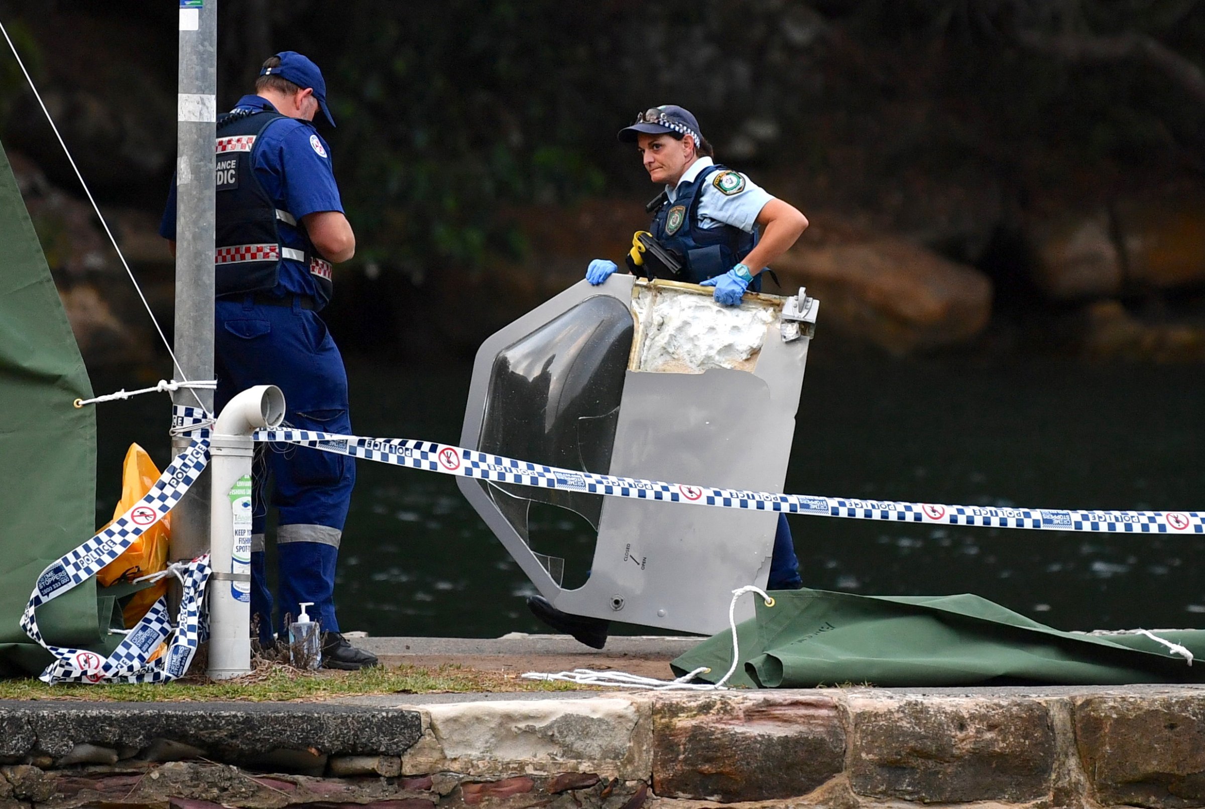 An Australian policewoman holds a piece of debris from a seaplane that crashed on Sunday killing six people at Apple Tree Bay located on the Hawkesbury River, north of Sydney
