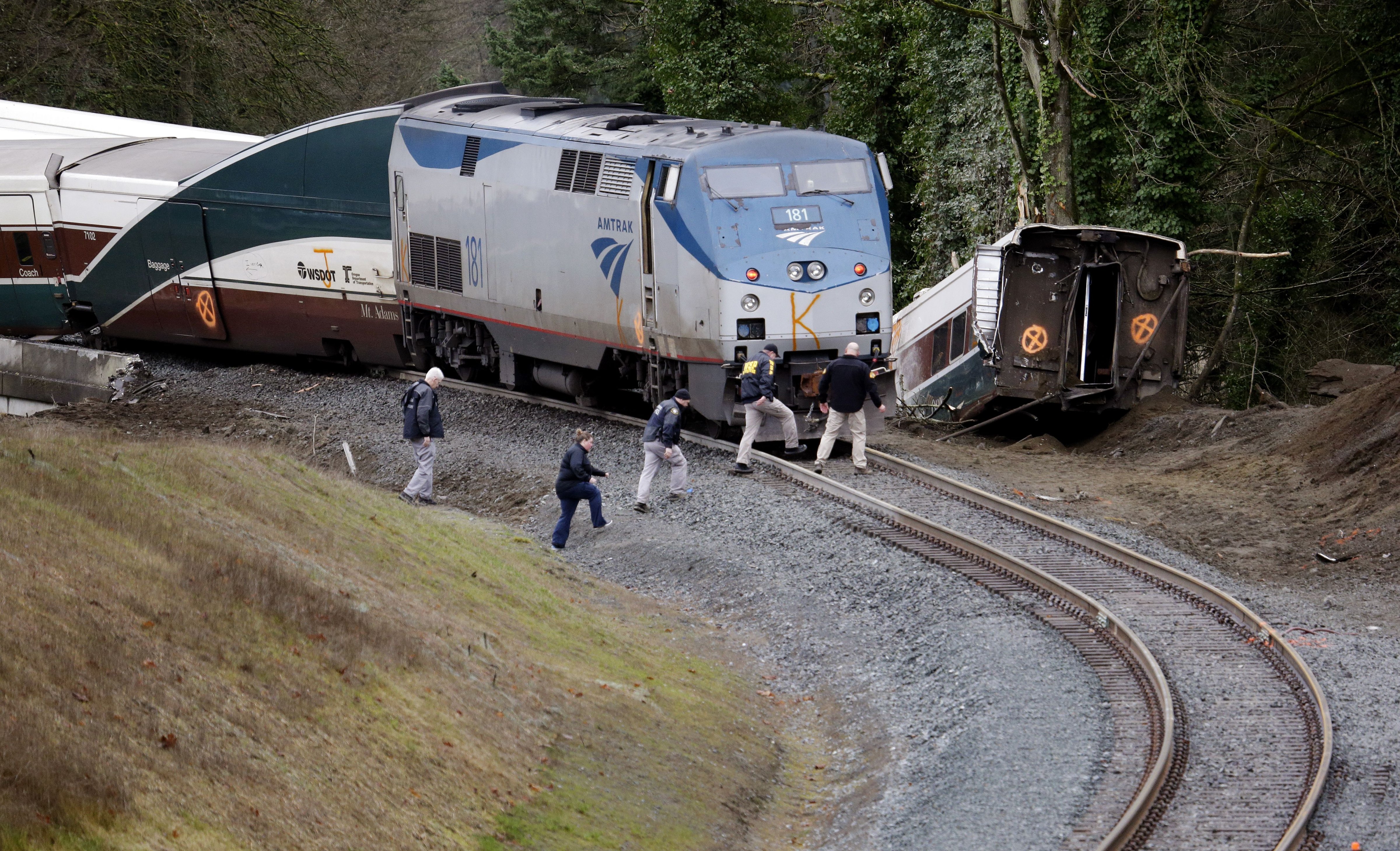 Police officials walk over tracks near a curve at the back of where an Amtrak train derailed above Interstate 5, in DuPont, Wash — Shutterstock/AP (Thompson/AP/REX/Shutterstock&mdash;Thompson/AP/REX/Shutterstock)