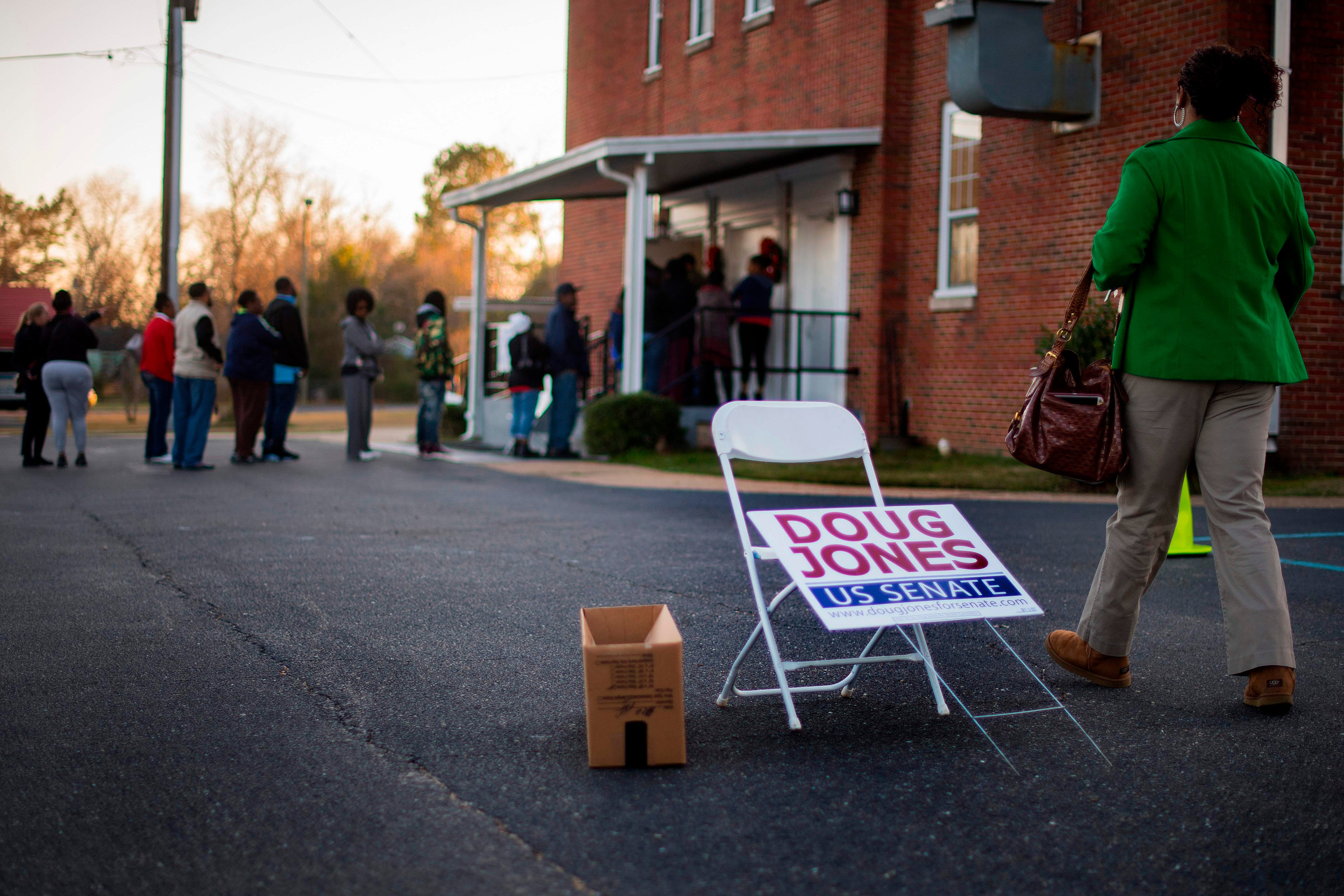 A woman passes a placard for Democratic Senatorial candidate Doug Jones as she walks over to get in the long line to vote at Beulah Baptist Church polling station in Montgomery, Alabama, on December 12, 2017. (JIM WATSON&mdash;AFP/Getty Images)