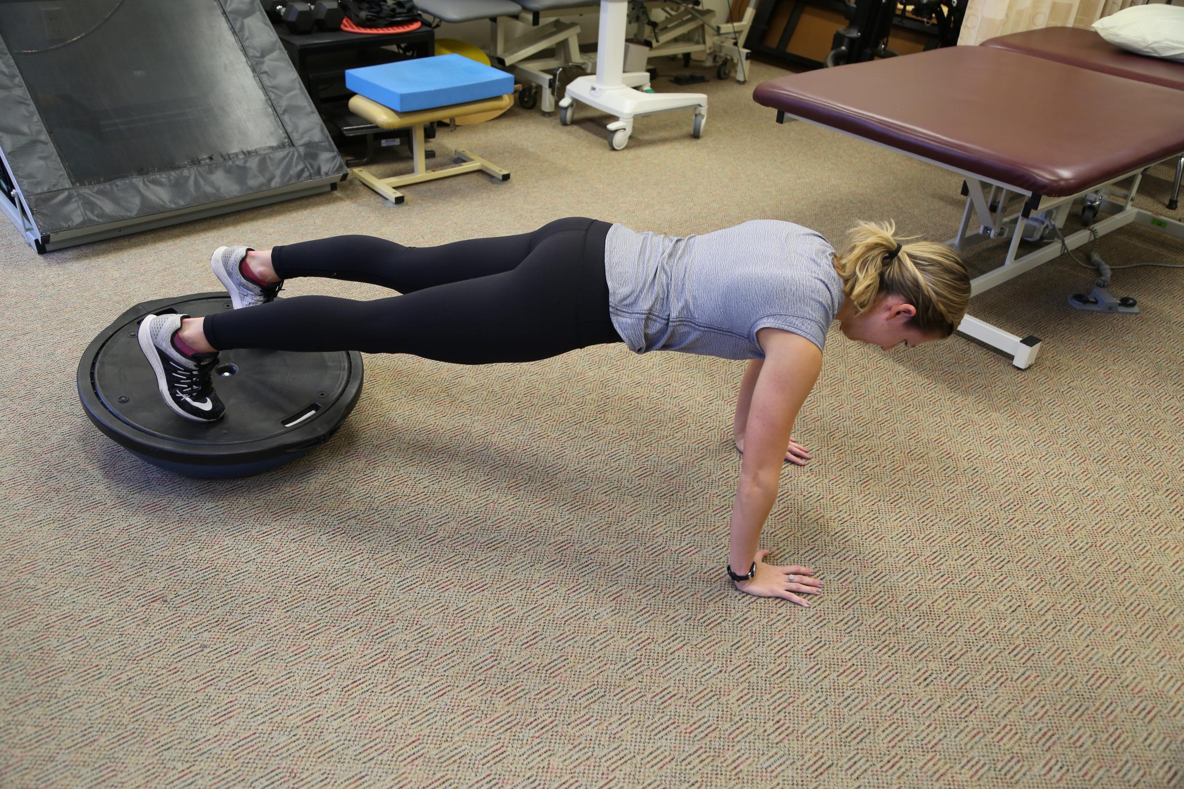 Kayla Borchers performs a plank on a Bosu ball. Stabilizing your body on an unstable surface is an effective way to strengthen the deep core muscles. New research finds that these muscles are commonly weak in runners, which often causes back pain.