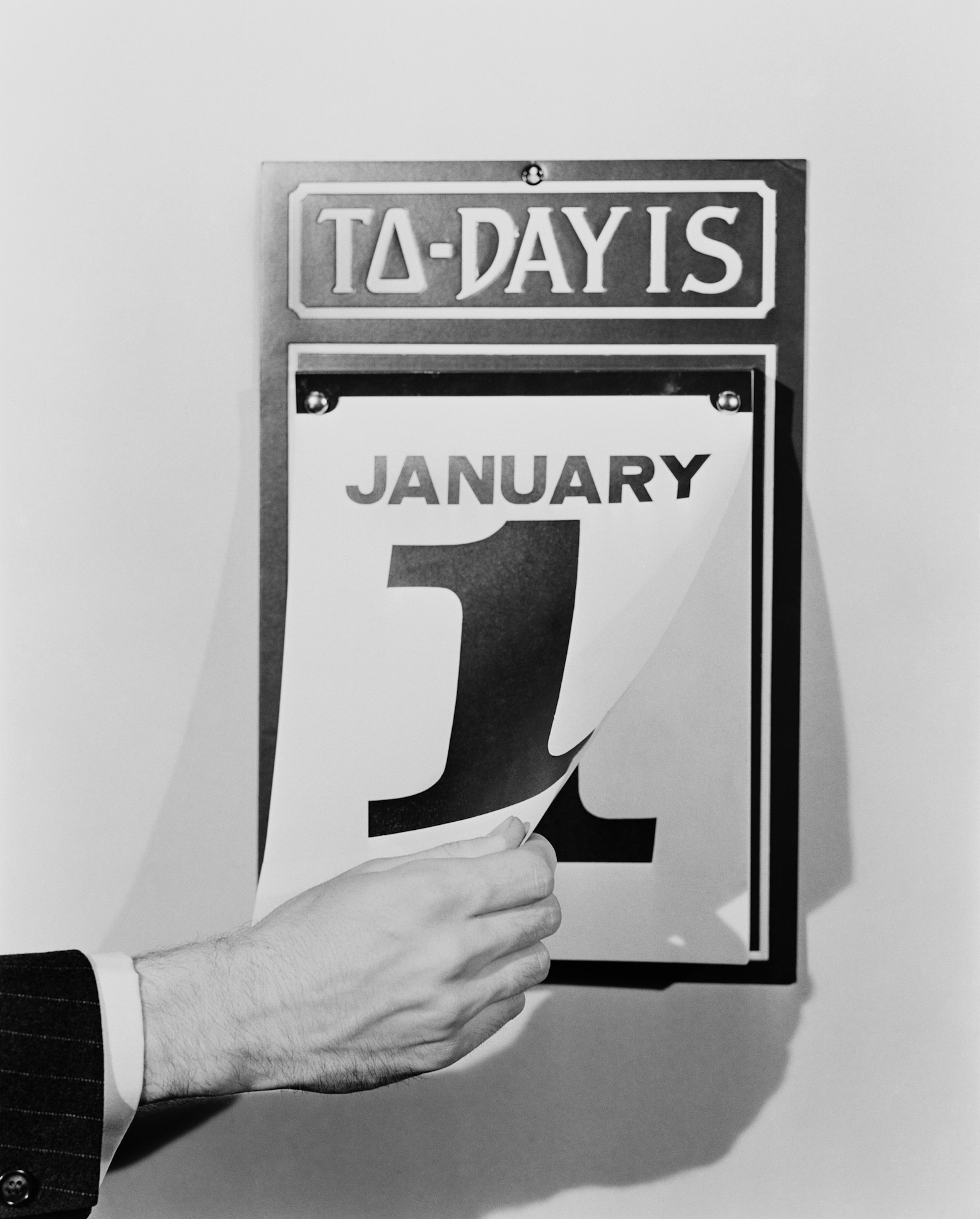 A man's hand tearing January 1 page off of daily wall calendar, circa 1930s (H. Armstrong Roberts—Retrofile/Getty Images)