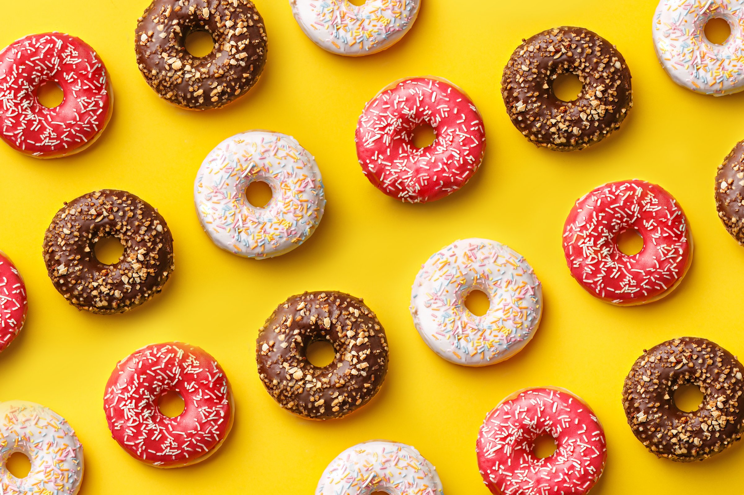 Flat lay donuts pattern on a yellow background. Top view
