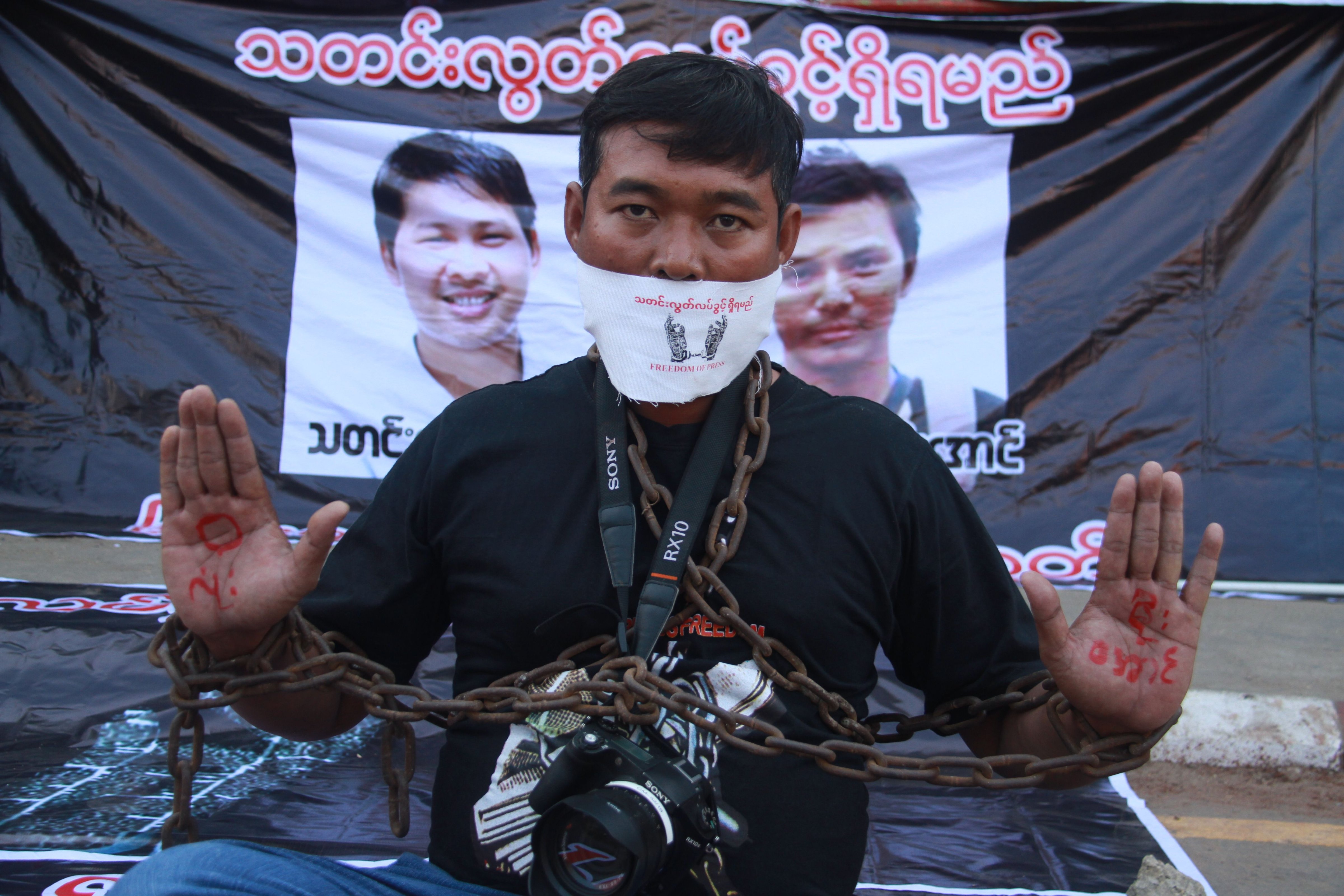 A journalist protests the arrest of Reuters journalists Wa Lone and Kyaw Soe Oo (pictured in posters behind) in Pyay, Myanmar on Dec. 27, 2017. (Thiha Lwin—AFP/Getty Images)