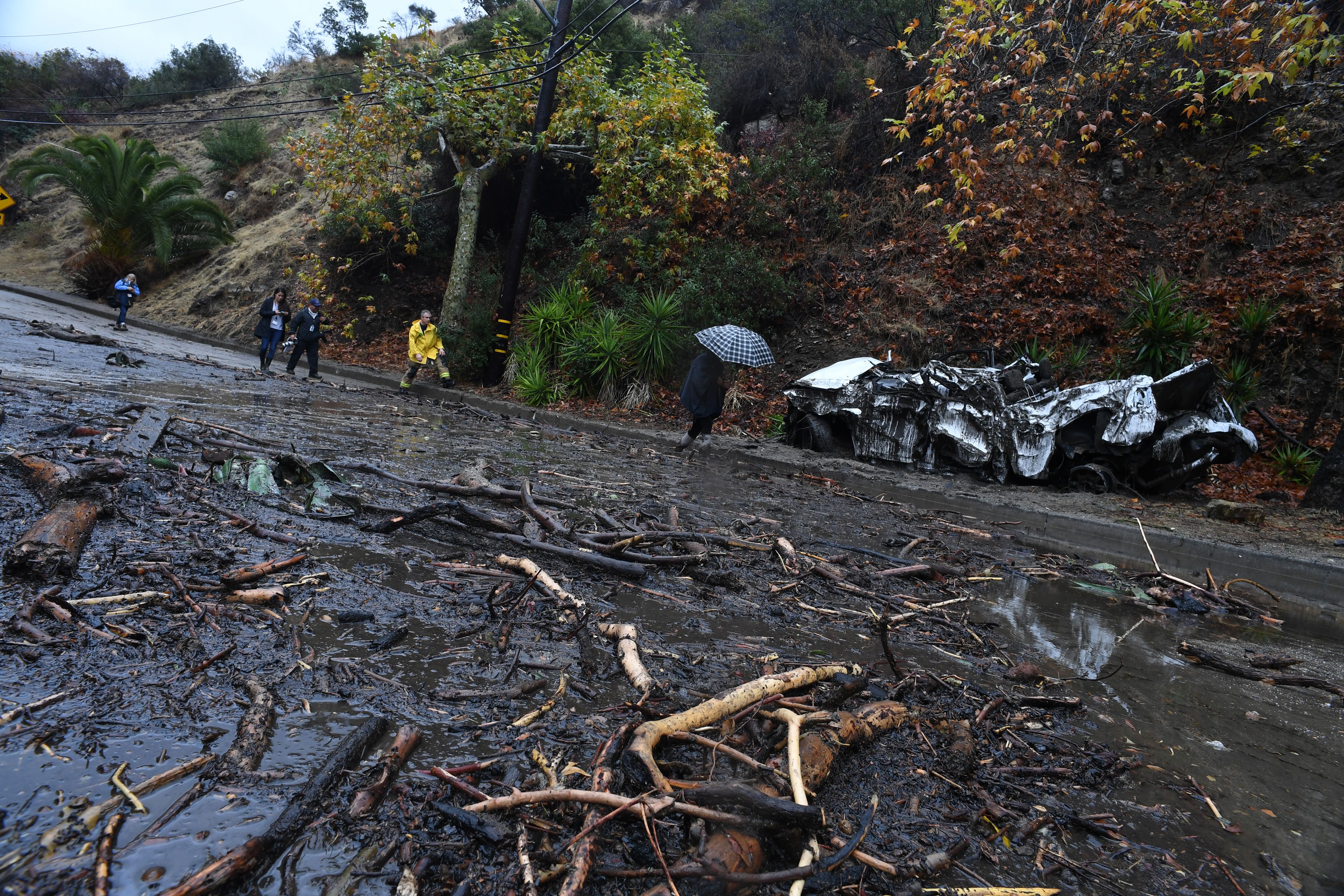 A firefighter (in yellow) instructs journalists to retreat to safer ground after a rain-driven mudslide destroyed two cars and damaged property in a neighborhood under mandatory evacuation in Burbank, California, January 9, 2018. (ROBYN BECK—AFP/Getty Images)