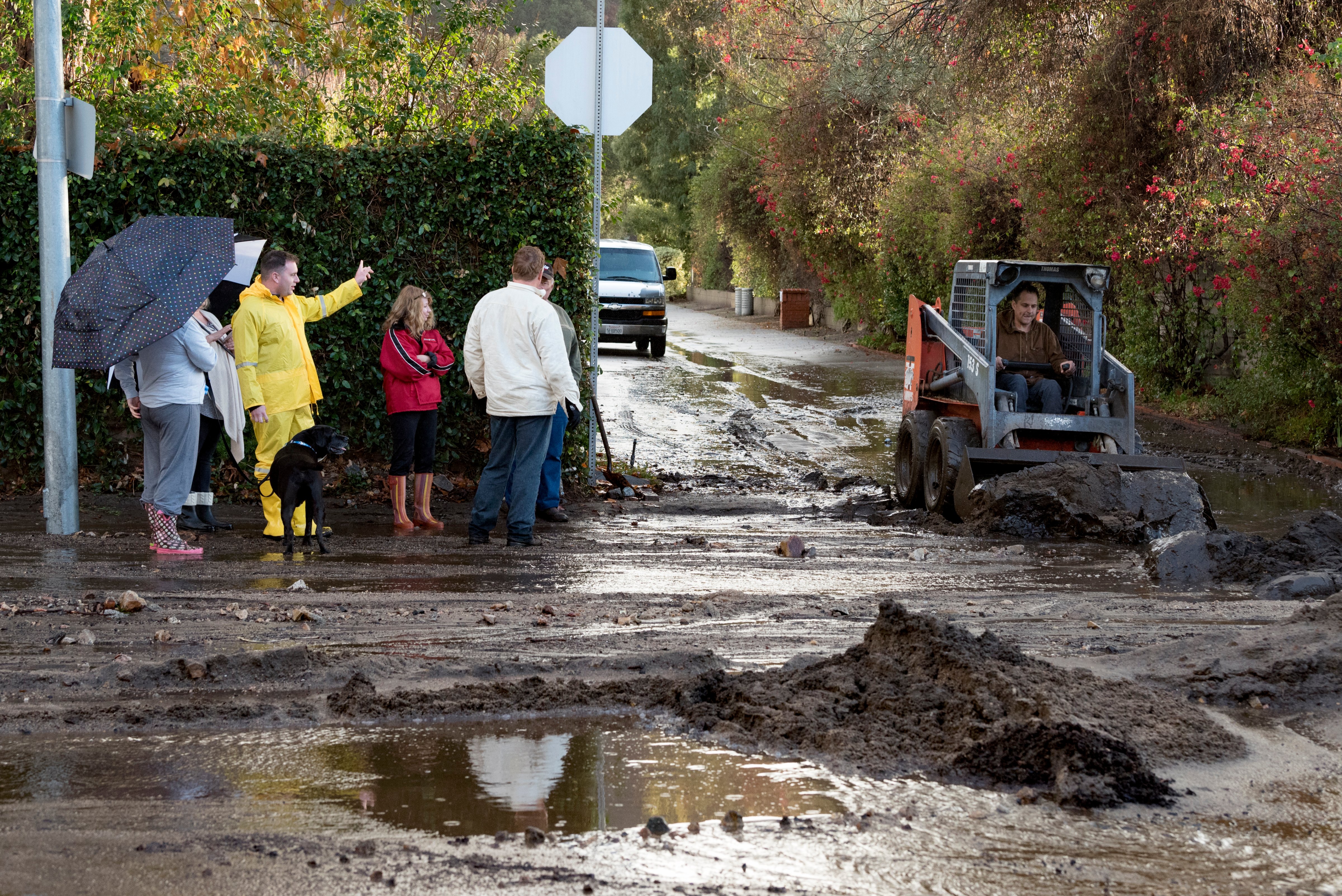 Residents look on as a man clears debris from a mudslide in Los Angeles, California on January 9, 2018. The deadly storm claimed the lives of 13 people in Santa Barbara County. Flash flooding also occurred in the recently burned areas of Ventura and Los Angeles counties. (NurPhoto—NurPhoto via Getty Images)