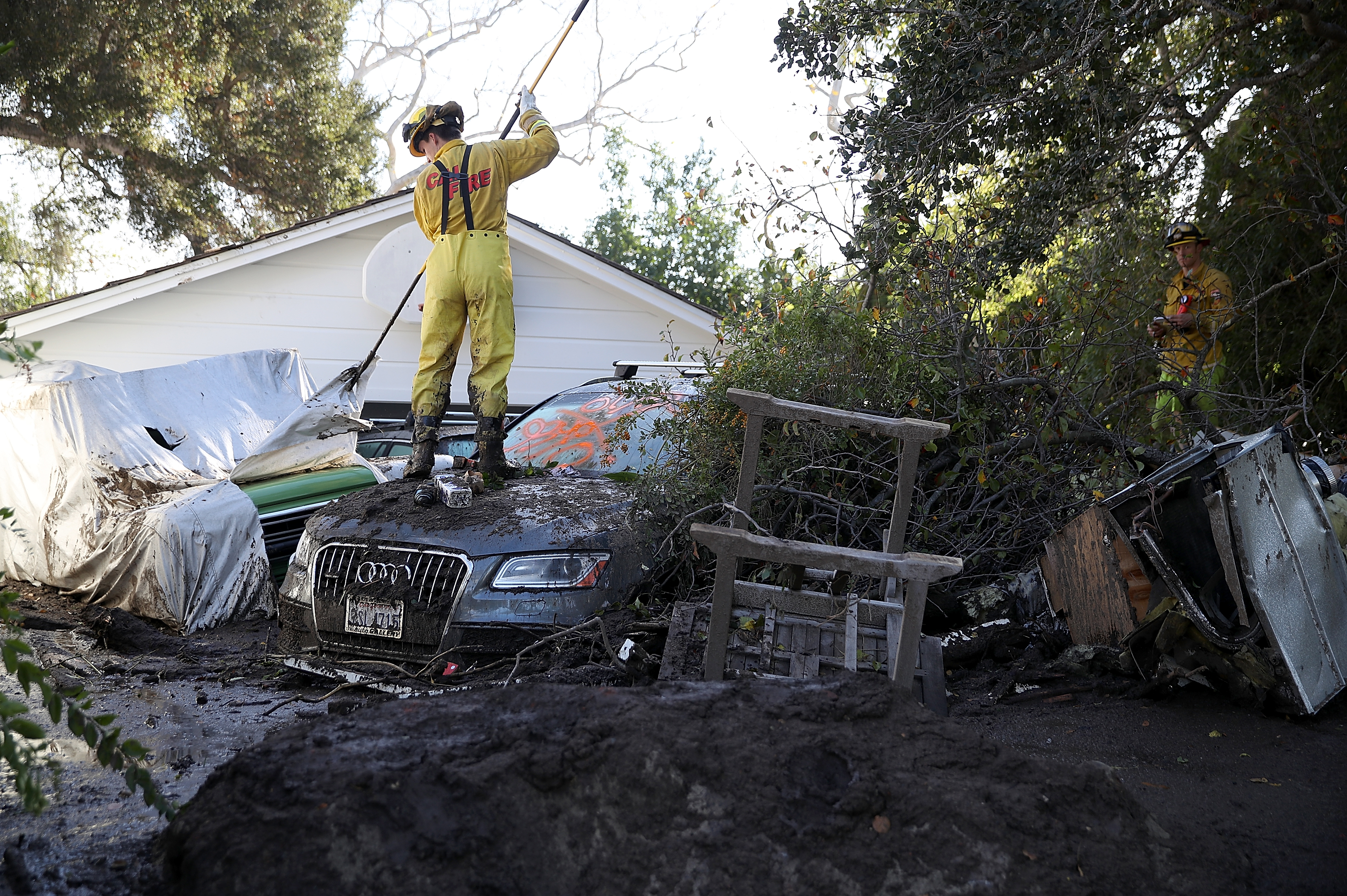 A Cal Fire firefighter looks through a car next to a home that was destroyed by a mudslide on January 12, 2018 in Montecito, California. (Justin Sullivan&mdash;Getty Images)