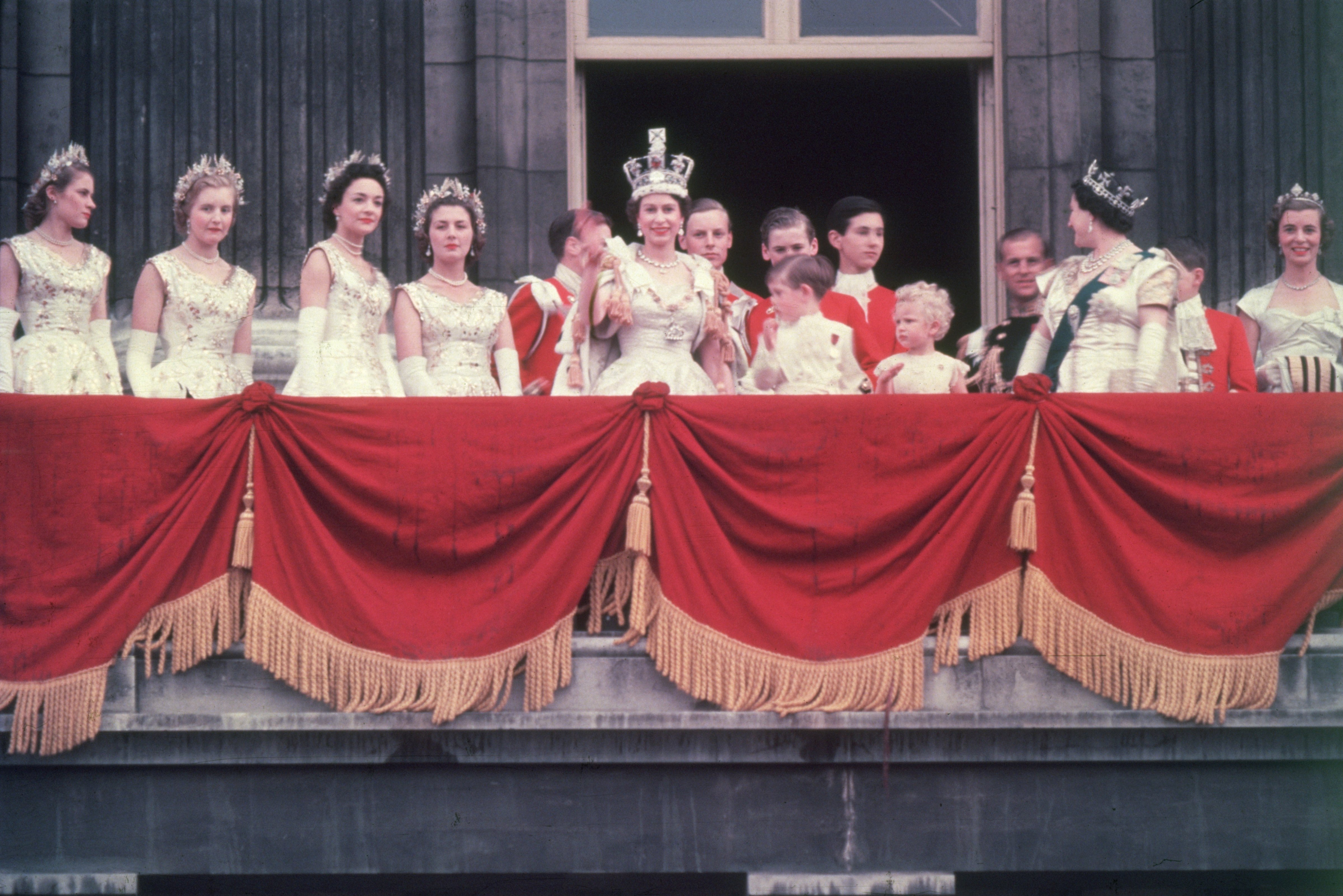 The newly crowned Queen Elizabeth II waves to the crowd from the balcony at Buckingham Palace on June 2, 1953. Her children Prince Charles and Princess Anne stand with her. (Hulton Archive&mdash;Getty Images)