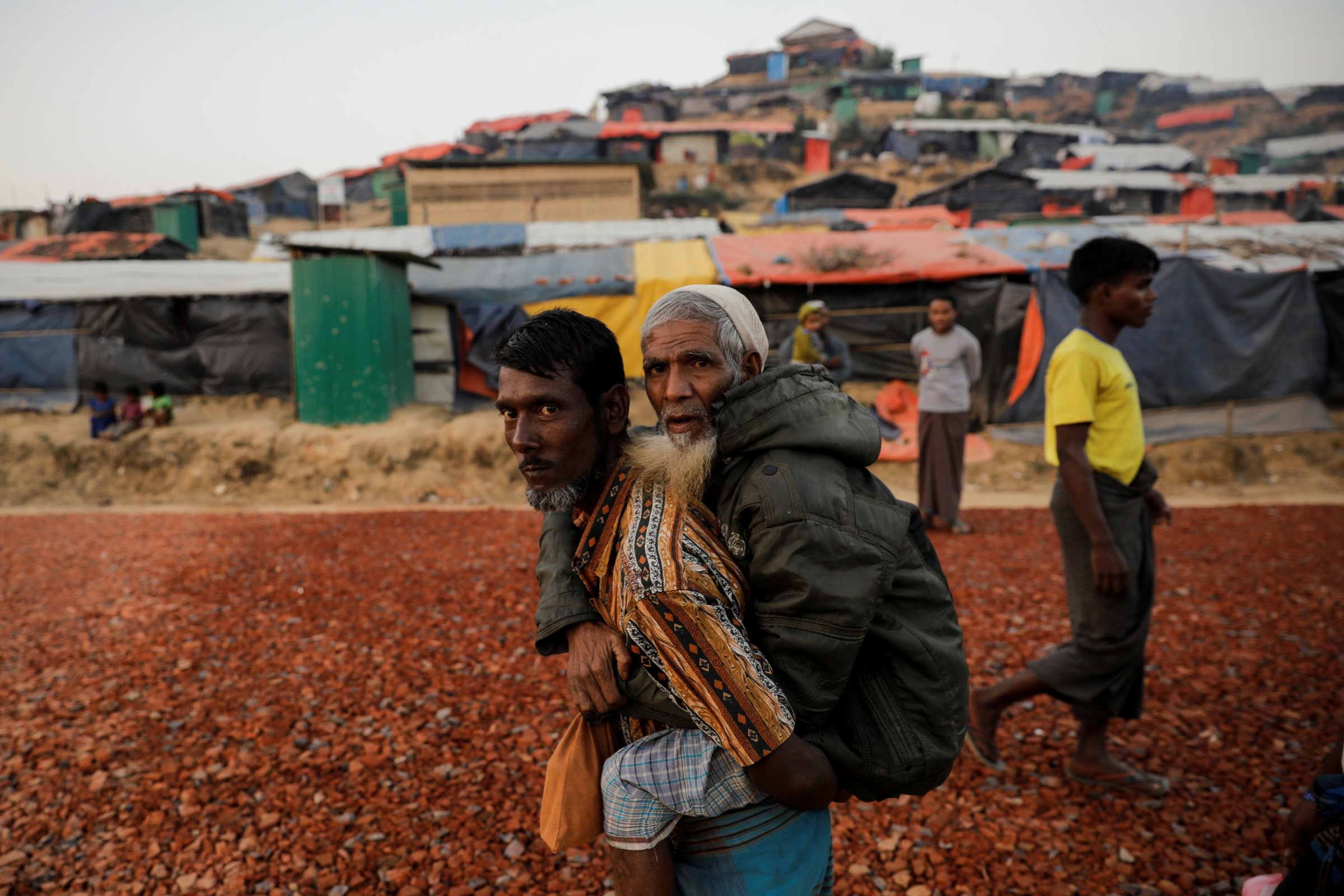 Rohingya refugee carries an elderly man at the Palongkhali refugee camp near Cox's Bazar