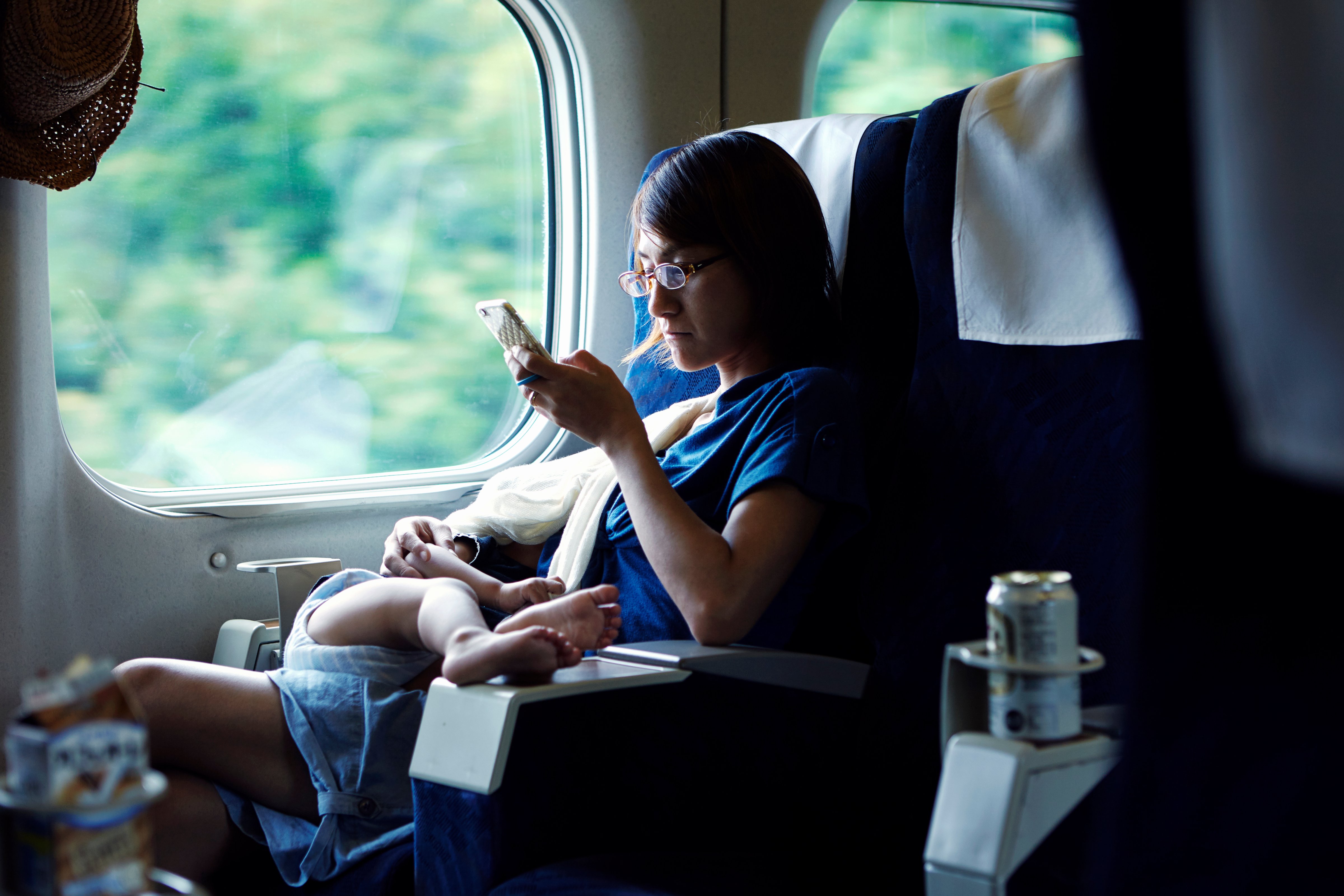 Mother using smartphone while breastfeeding on train