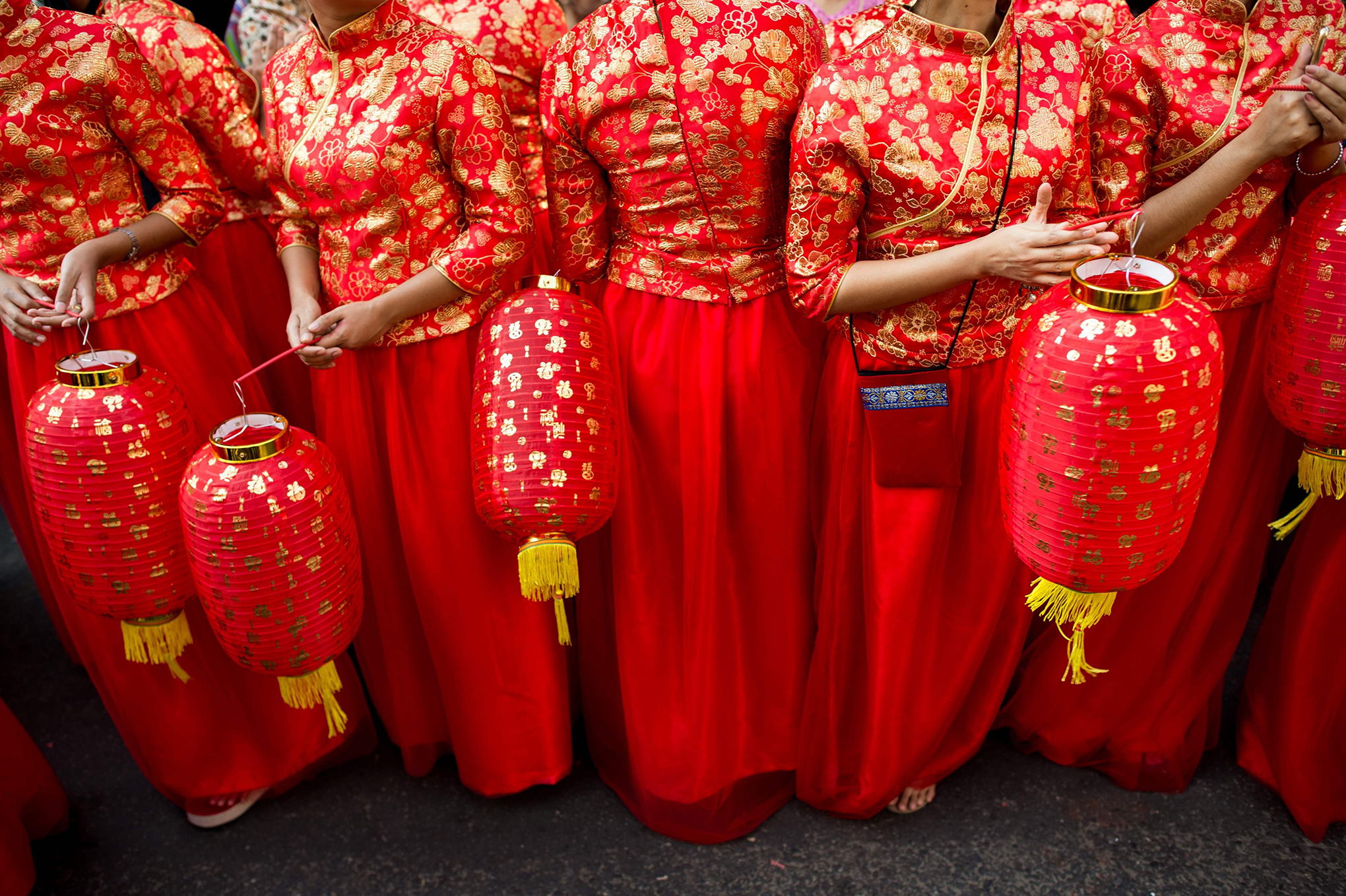 Young women in traditional Chinese costumes hold lanterns as they take part in celebrations marking the first day of the Lunar New Year in Yangon's Chinatown district on Feb. 16, 2018.