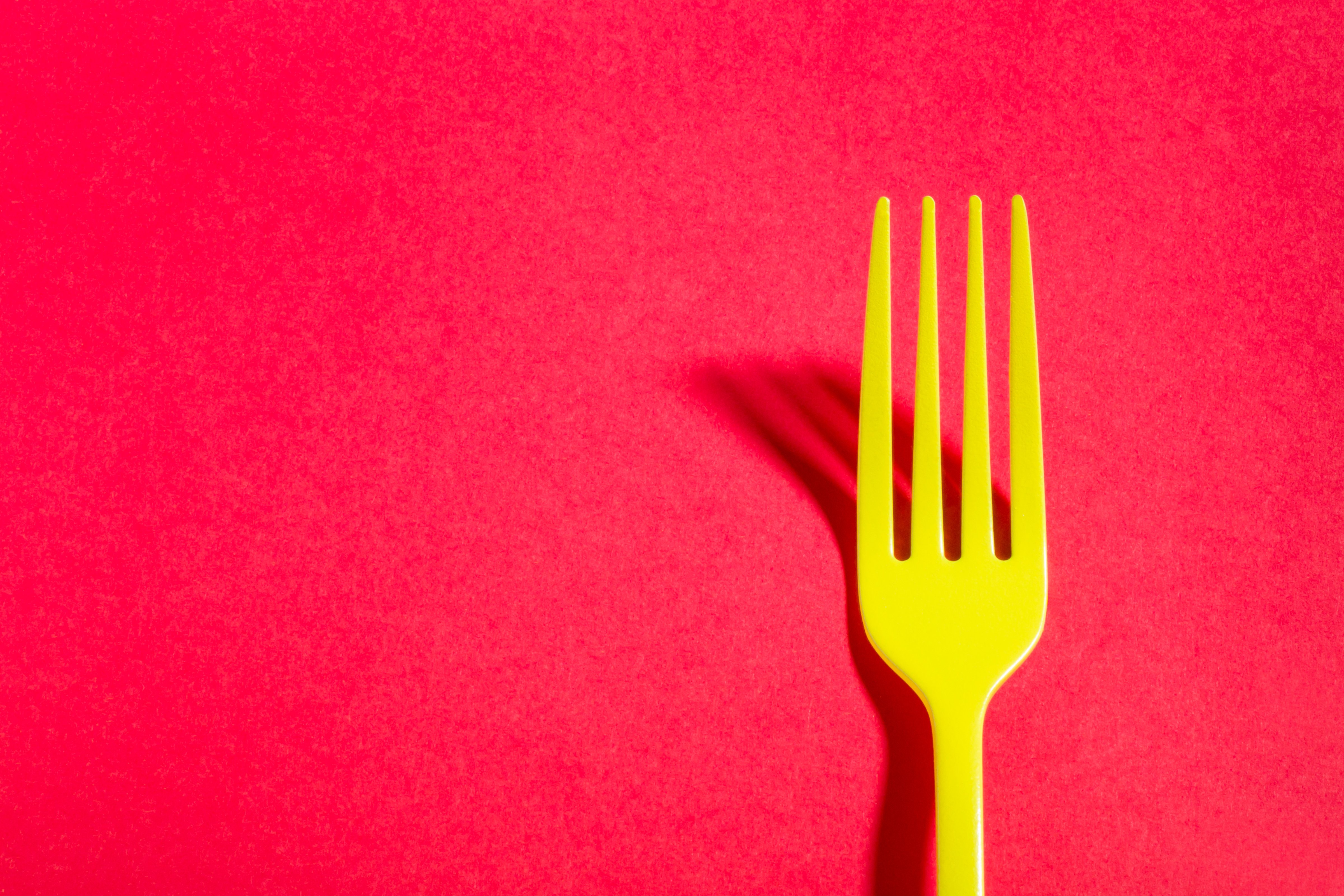 Clos-Up Of Yellow Fork Against Red Background