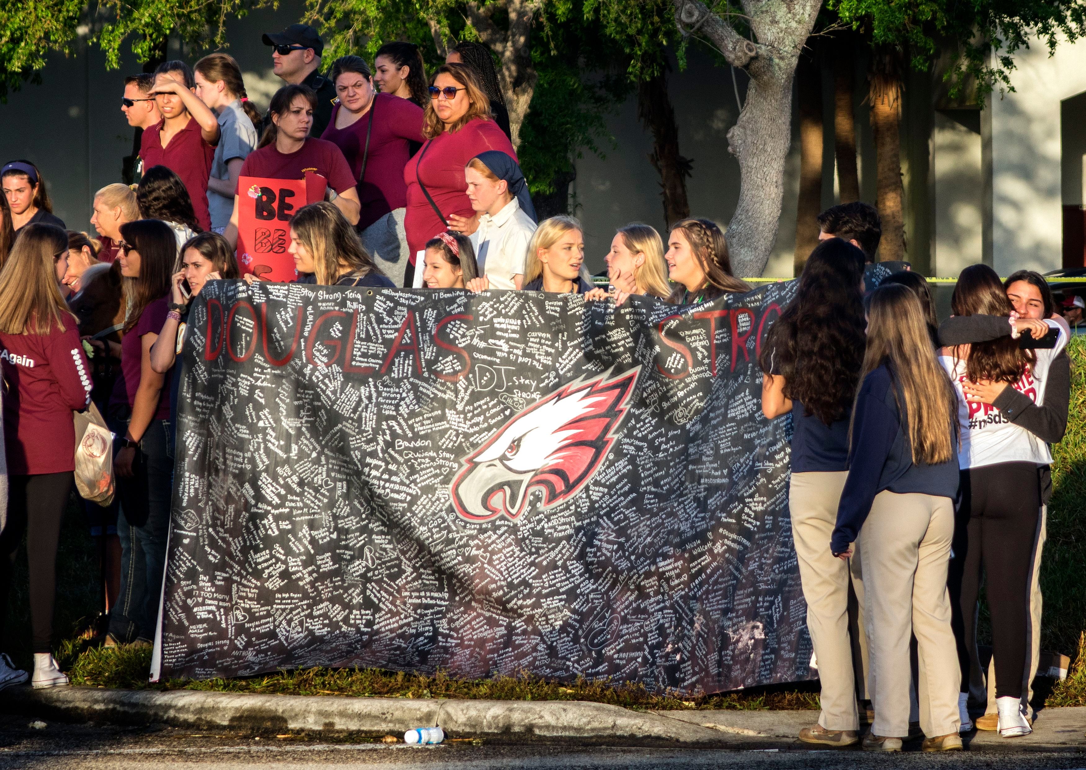 A banner bearing messages is held as parents and students arrive at Marjory Stoneman Douglas High School in Parkland, Florida, USA, 28 February 2018, for the school's reopening, two weeks after the mass shootings at the school. (Cristobal Herrera—EPA-EFE/REX/Shutterstock)