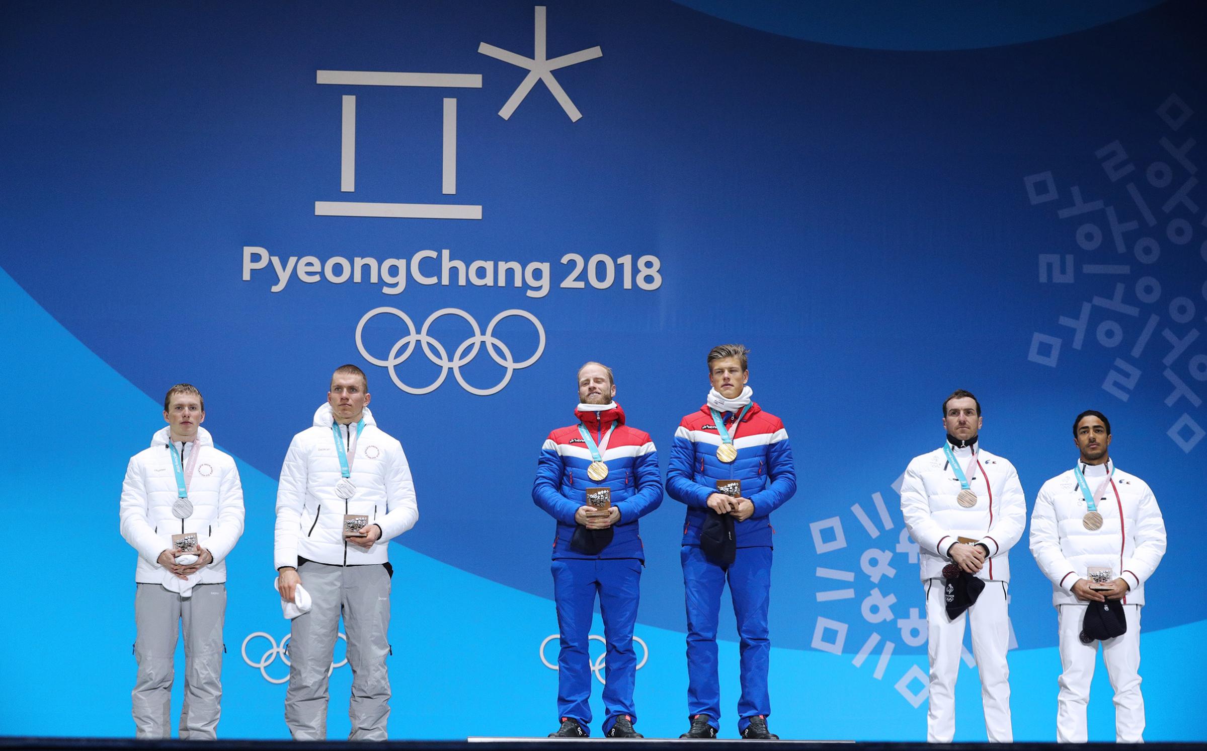 Gold medalists, Norway's Martin Johnsrud Sundby and Johannes Hoesflot Klaebo during a victory ceremony for the men's cross-country skiing team sprint free event at the 2018 Winter Olympic Games.
