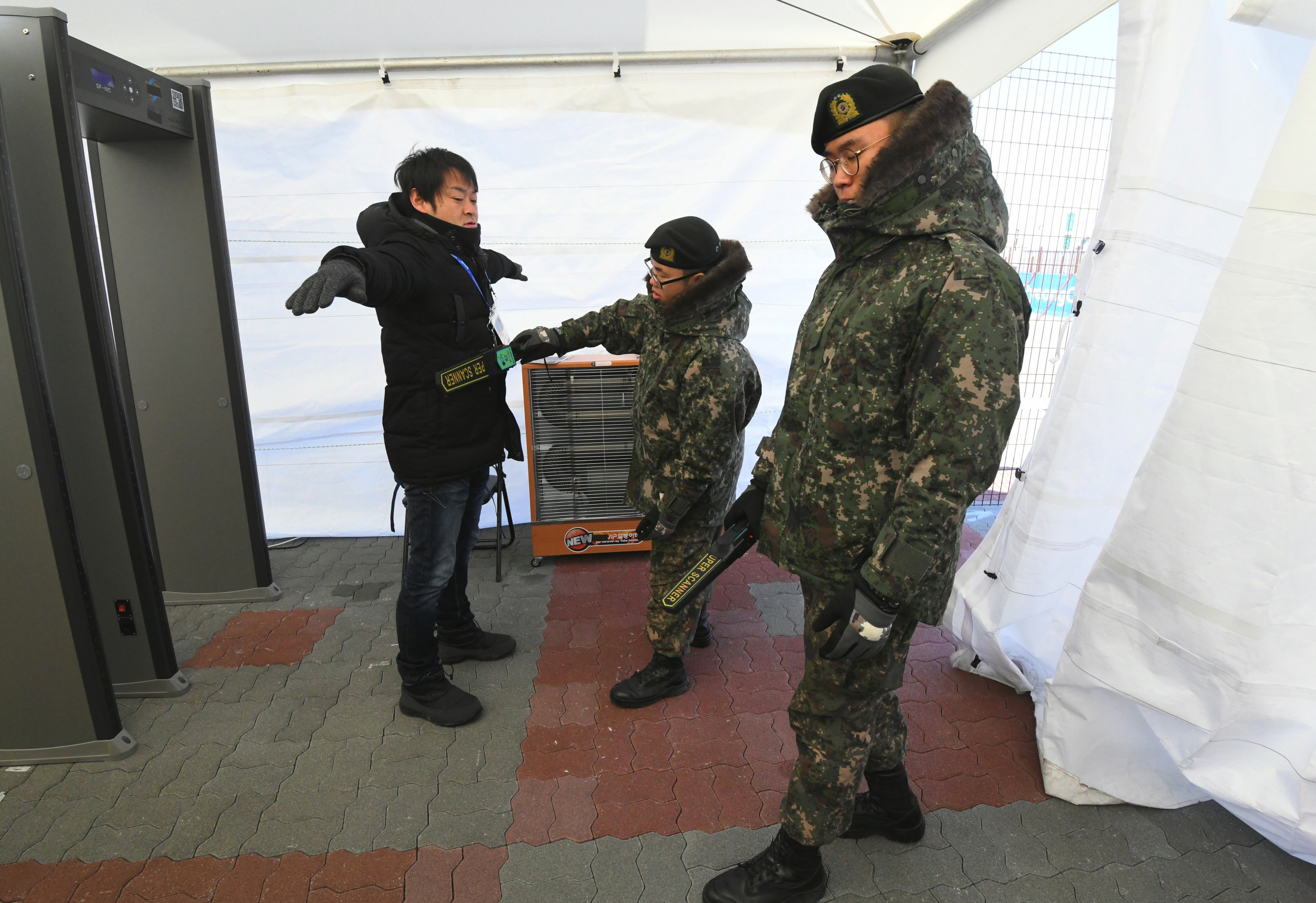 South Korean soldiers inspect a visitor at a security checkpoint as they replace security guards showing symptoms of the norovirus at the Gangneung Ice Arena in Gangneung on February 6, 2018 ahead of the PyeongChang 2018 Winter Olympic Games. (JUNG YEON-JE—AFP/Getty Images)