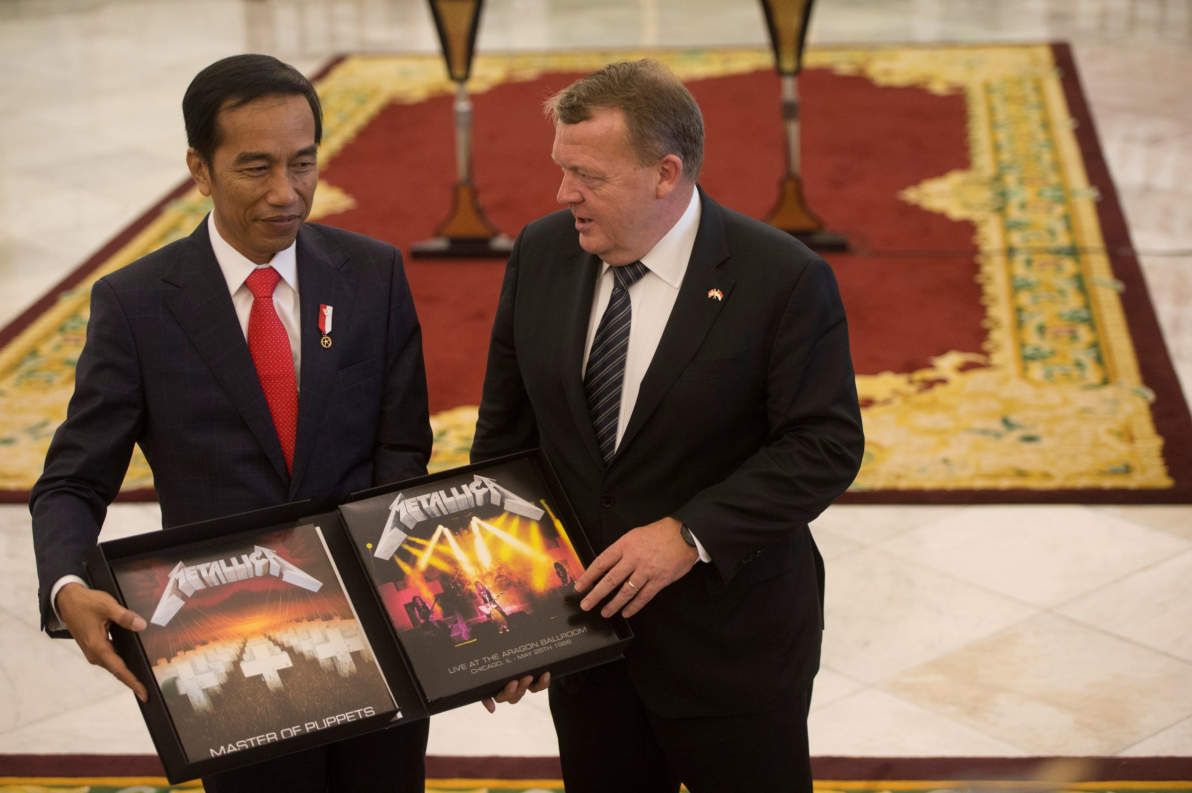 Denmark Prime Minister Lars Lokke Rasmussen gives a vinyl record of the heavy metal band Metallica to Indonesian President Joko Widodo after a joint press conference at the Presidential Palace in Bogor