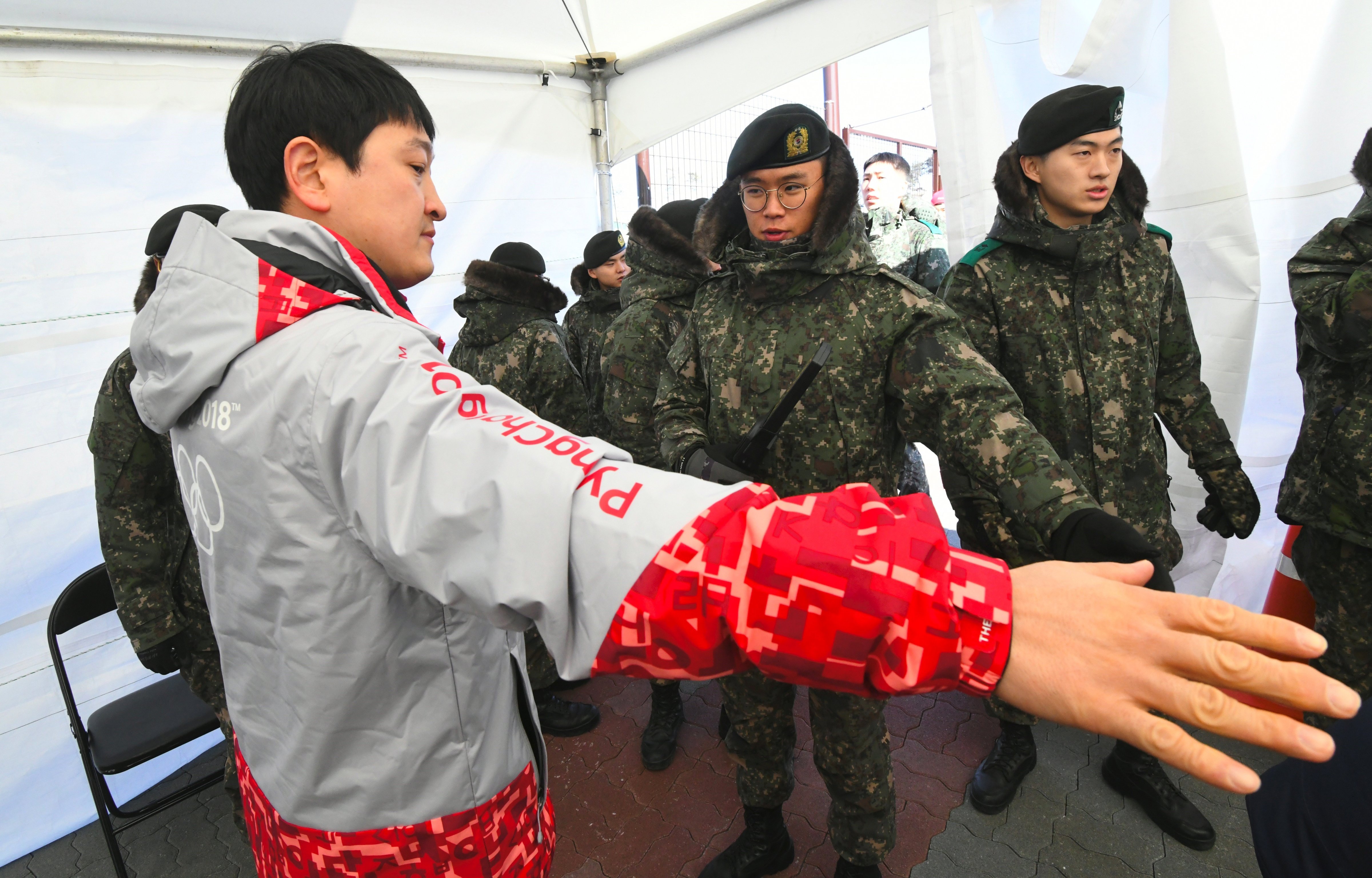 South Korean soldiers inspect a visitor at a security checkpoint as they replace security guards showing symptoms of the norovirus at the Gangneung Ice Arena in Gangneung on February 6, 2018 ahead of the Pyeongchang 2018 Winter Olympic Games.
                      According to officials at Korea Centers for Disease Control and Prevention and the PyeongChang Organizing Committee, three out of 41 guards who suffered from diarrhea and vomiting were diagnosed with having the norovirus on February 5. (JUNG YEON-JE/AFP—Getty Images)