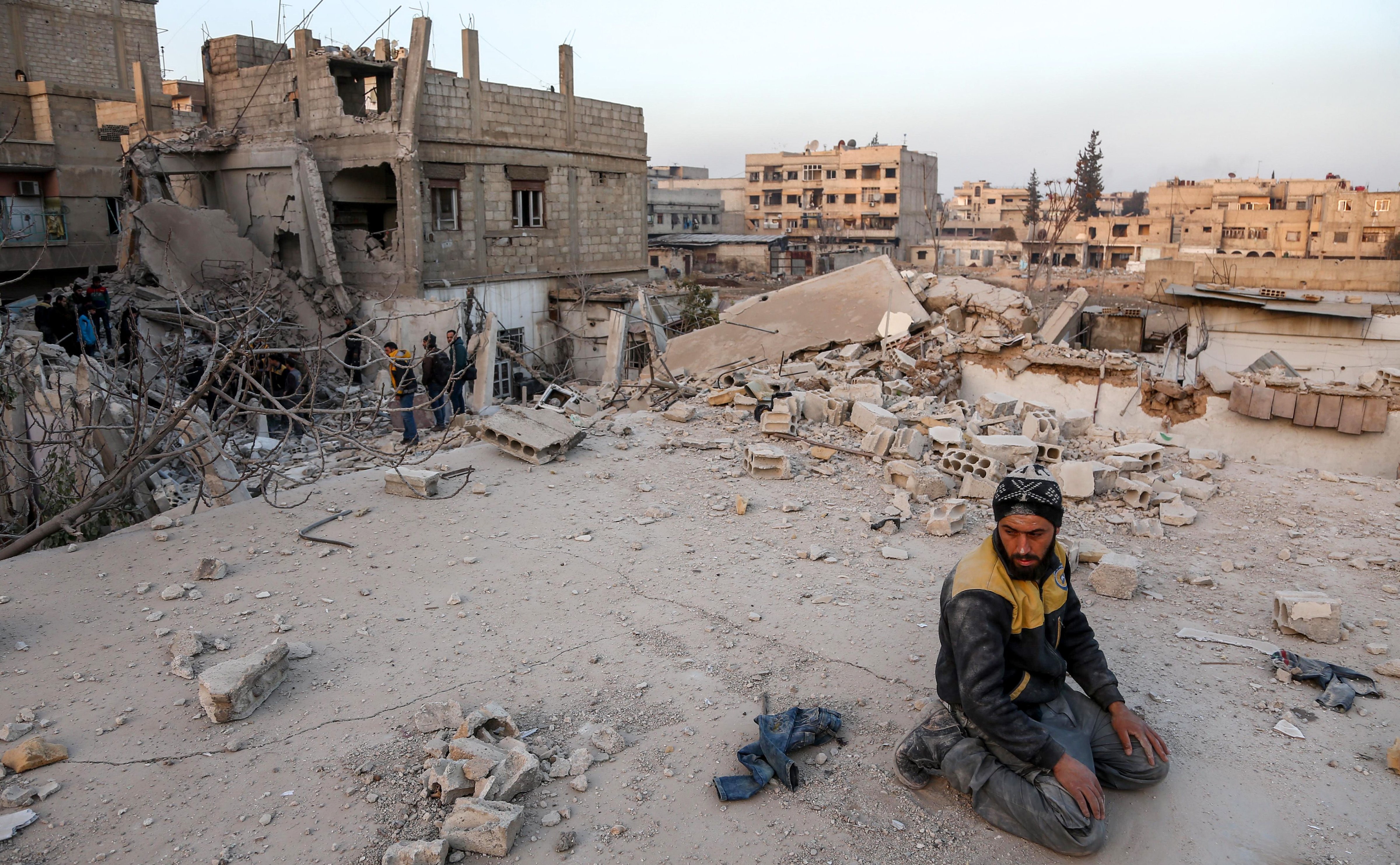A Syrian civil defense volunteer performs ritual sunset prayers next to the site of a building that collapsed following reported regime air strikes in the rebel-held town of Arbin, in the besieged Eastern Ghouta region on the outskirts of the capital Damascus, on February 6, 2018. (ABDULMONAM EASSA&mdash;AFP/Getty Images)