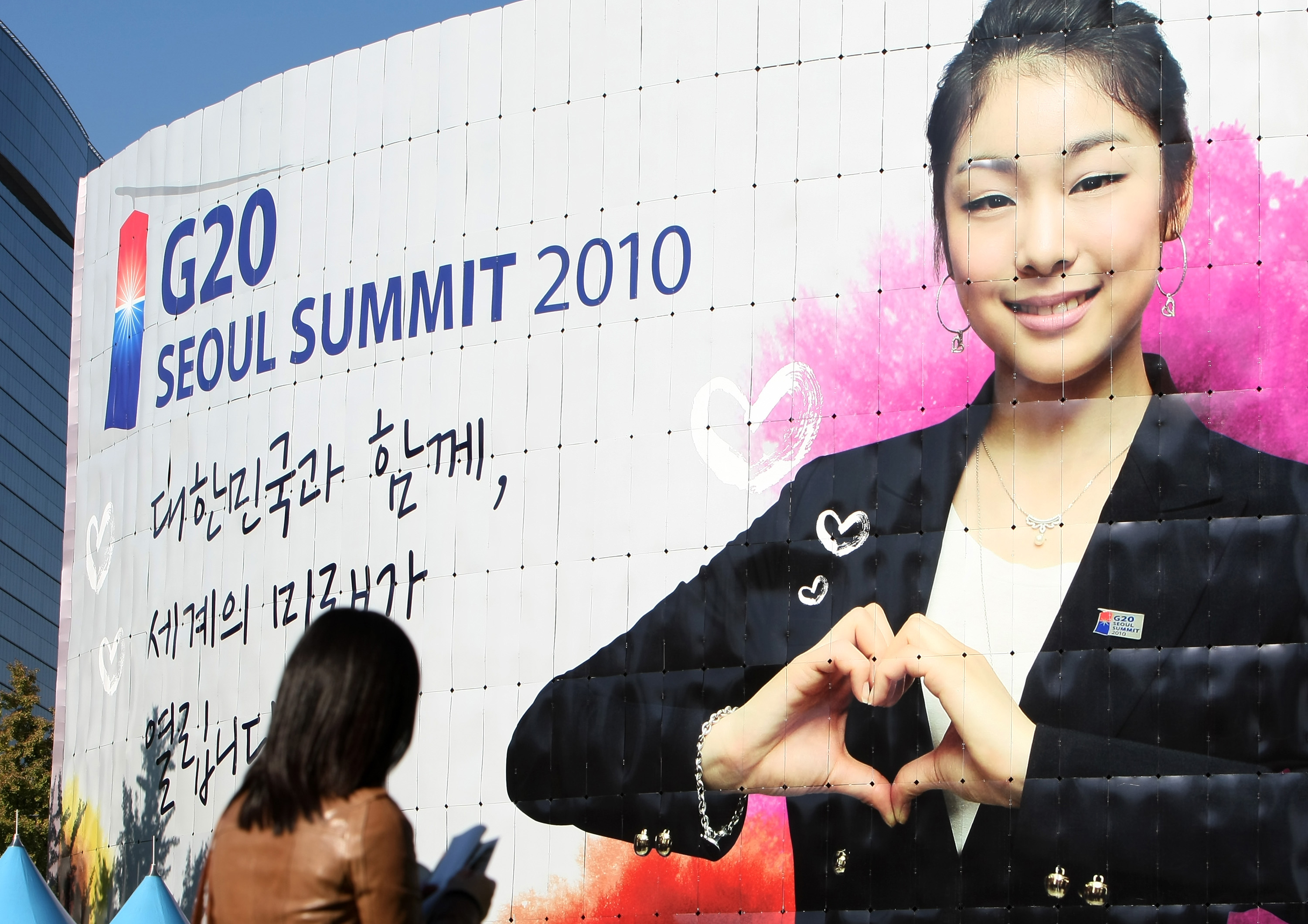 Pedestrians walk past Seoul City Hall, which is covered with a billboard showing a picture of Olympic figure skating gold medalist Kim Yuna, for the Group of 20 (G-20) summit in Seoul, South Korea, on Saturday, Oct. 30, 2010. Photographer: SeongJoon Cho/Bloomberg via Getty Images (Bloomberg&mdash;Bloomberg via Getty Images)