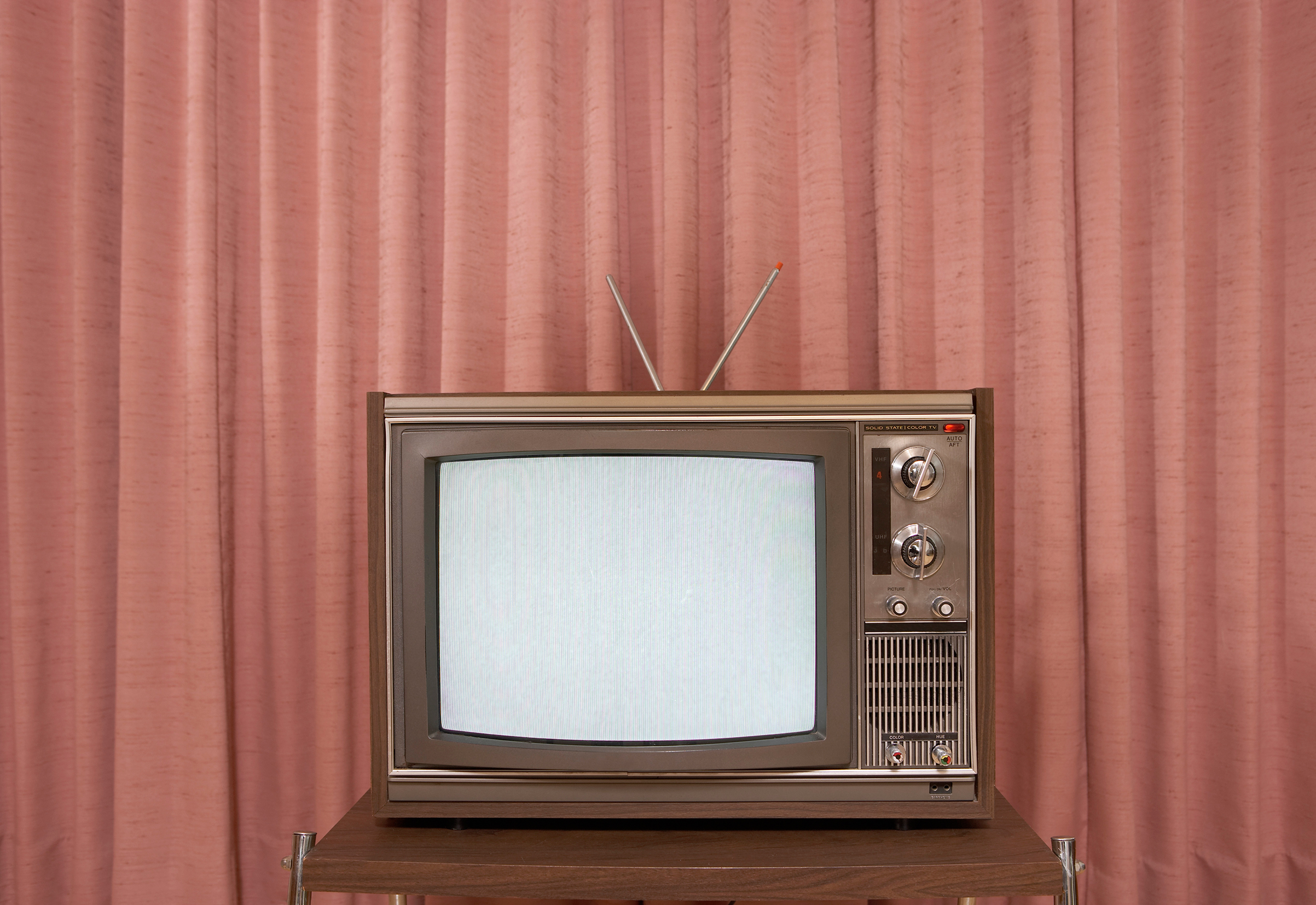 Old television on stand, in front of curtain