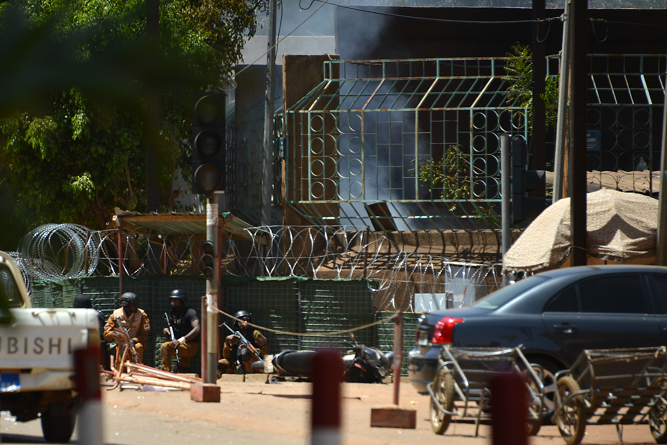 Security personnel take cover as smoke billows from The Institute Francais in Ouagadougou on March 2, 2018, as the capital of Burkina Faso came under multiple attacks targeting the French embassy, the French cultural centre and the country's military headquarters.
                      Witnesses said five armed men got out of a car and opened fire on passersby before heading towards the embassy, in the centre of the city. Other witnesses said there was an explosion near the headquarters of the Burkinabe armed forces and the French cultural centre, which are located about a kilometre (half a mile) from the site of the first attack.
                       / AFP PHOTO / Ahmed OUOBA        (Photo credit should read AHMED OUOBA/AFP/Getty Images) (AHMED OUOBA&mdash;AFP/Getty Images)
