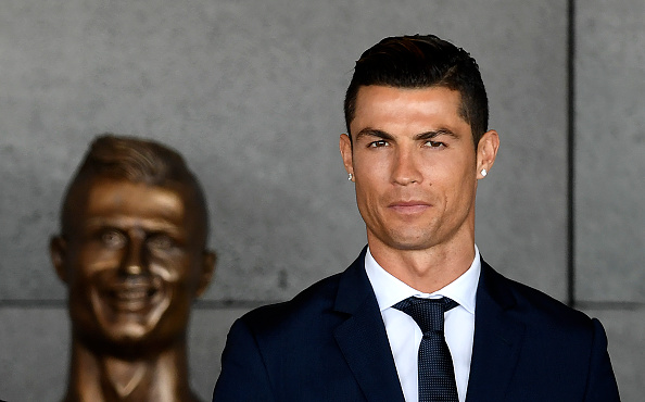 Cristiano Ronaldo stands in front of a bust of himself at Madeira Airport