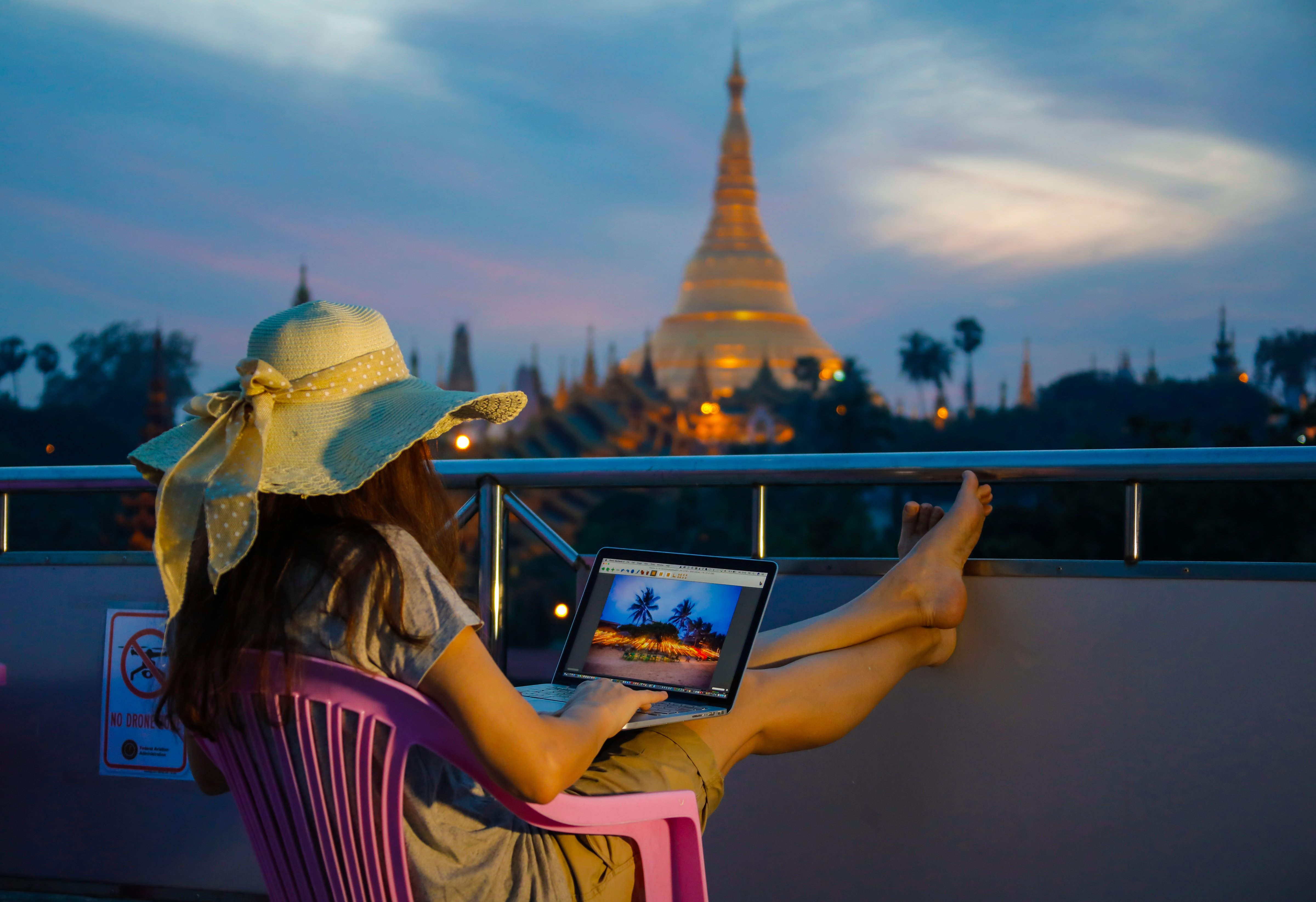 A tourist watches the famous Shwedagon Pagoda in Yangon, Burma while working on her laptop (EyesWideOpen&mdash;Getty Images)
