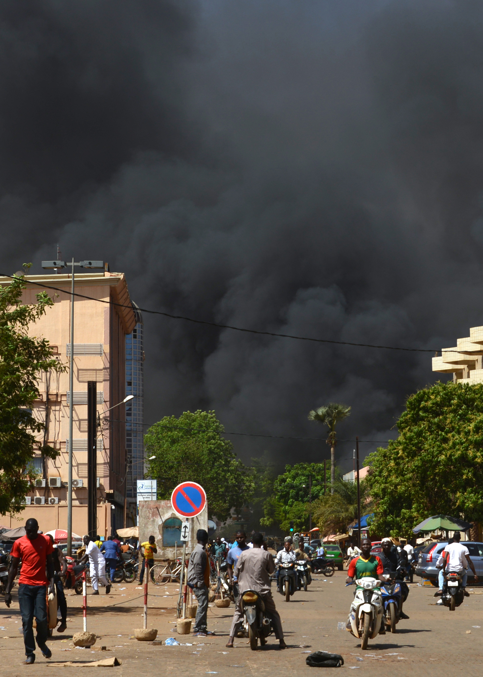 People watch as black smoke rises as the capital of Burkina Faso came under multiple attacks on March 2, 2018, targeting the French embassy, the French cultural centre and the country's military headquarters. Witnesses said five armed men got out of a car and opened fire on passersby before heading towards the embassy, in the centre of the city. Other witnesses said there was an explosion near the headquarters of the Burkinabe armed forces and the French cultural centre, which are located about a kilometre (half a mile) from the site of the first attack. AHMED OUOBA/AFP/Getty Images (AHMED OUOBA&mdash;AFP/Getty Images)