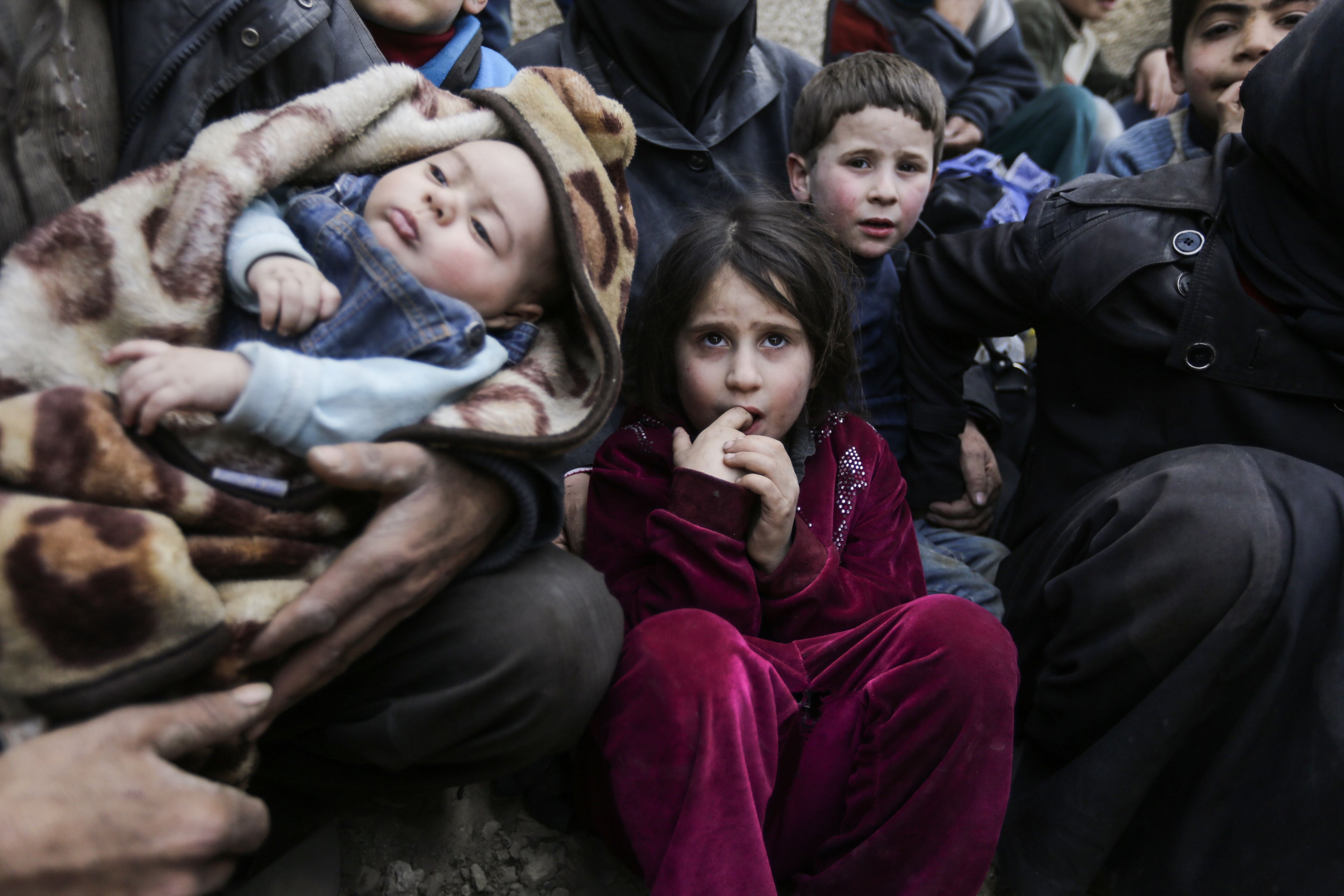 Syrian children sit while awaiting to be evacuated from the Eastern Ghouta enclave in Hawsh al-Ashaari, on March 15, 2018. (Louai Beshara—AFP/Getty Images)