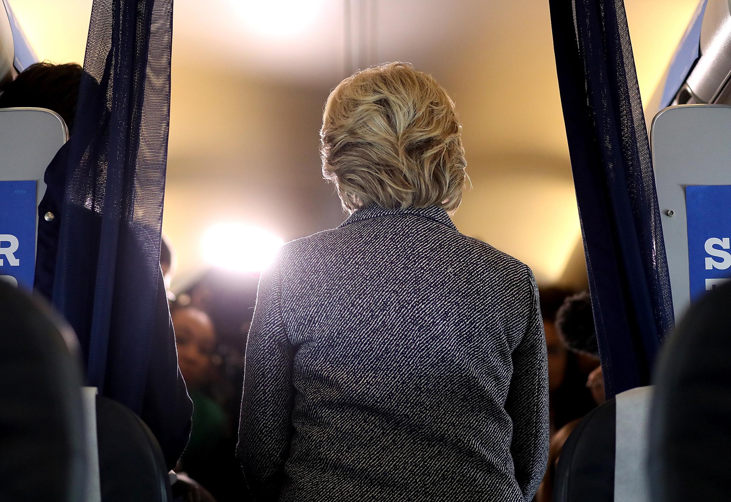 Hillary Clinton speaks to reporters aboard her campaign plane