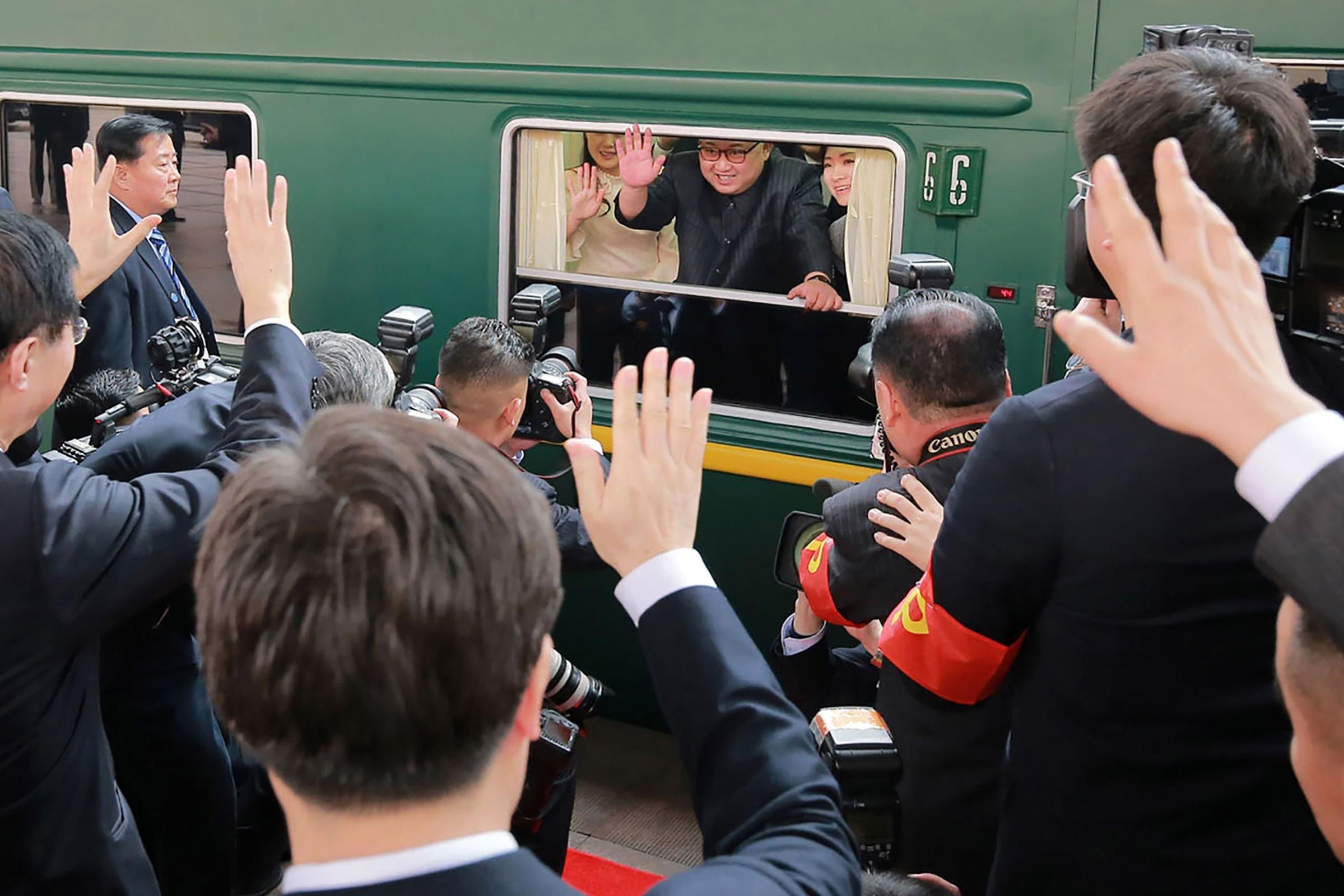 North Korean leader Kim Jong Un waves from his train as it prepares to depart from Beijing railway station