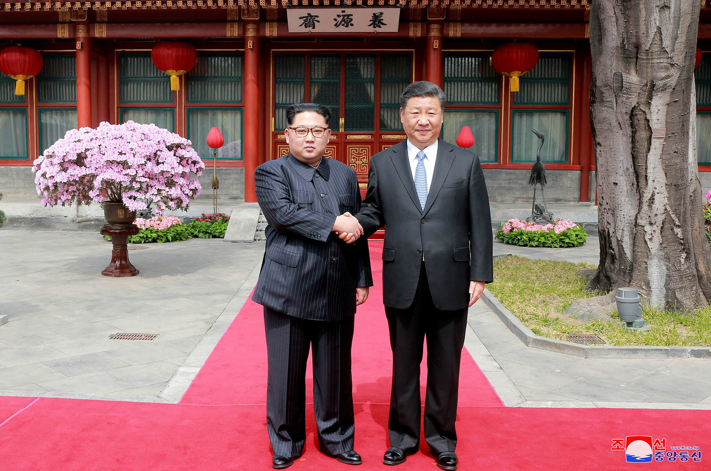 Kim and Xi shake hands at the Diaoyutai State Guesthouse on March 27; Kim waves from his armored train before departing Beijing following his surprise visit (KCNA/KNS/AP)