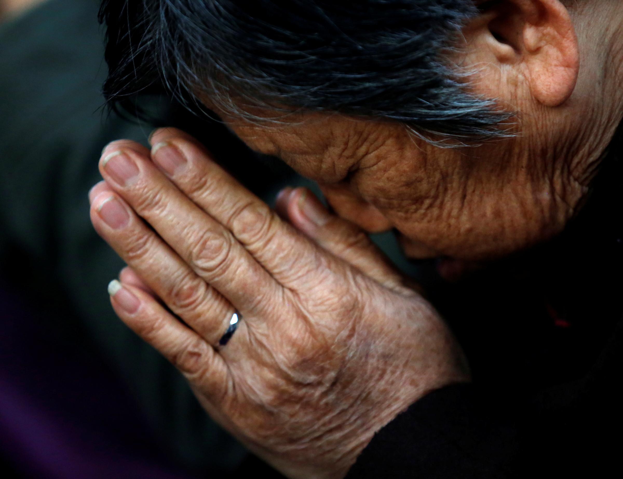 FILE PHOTO: A believer prays during a weekend mass at an underground Catholic church in Tianjin