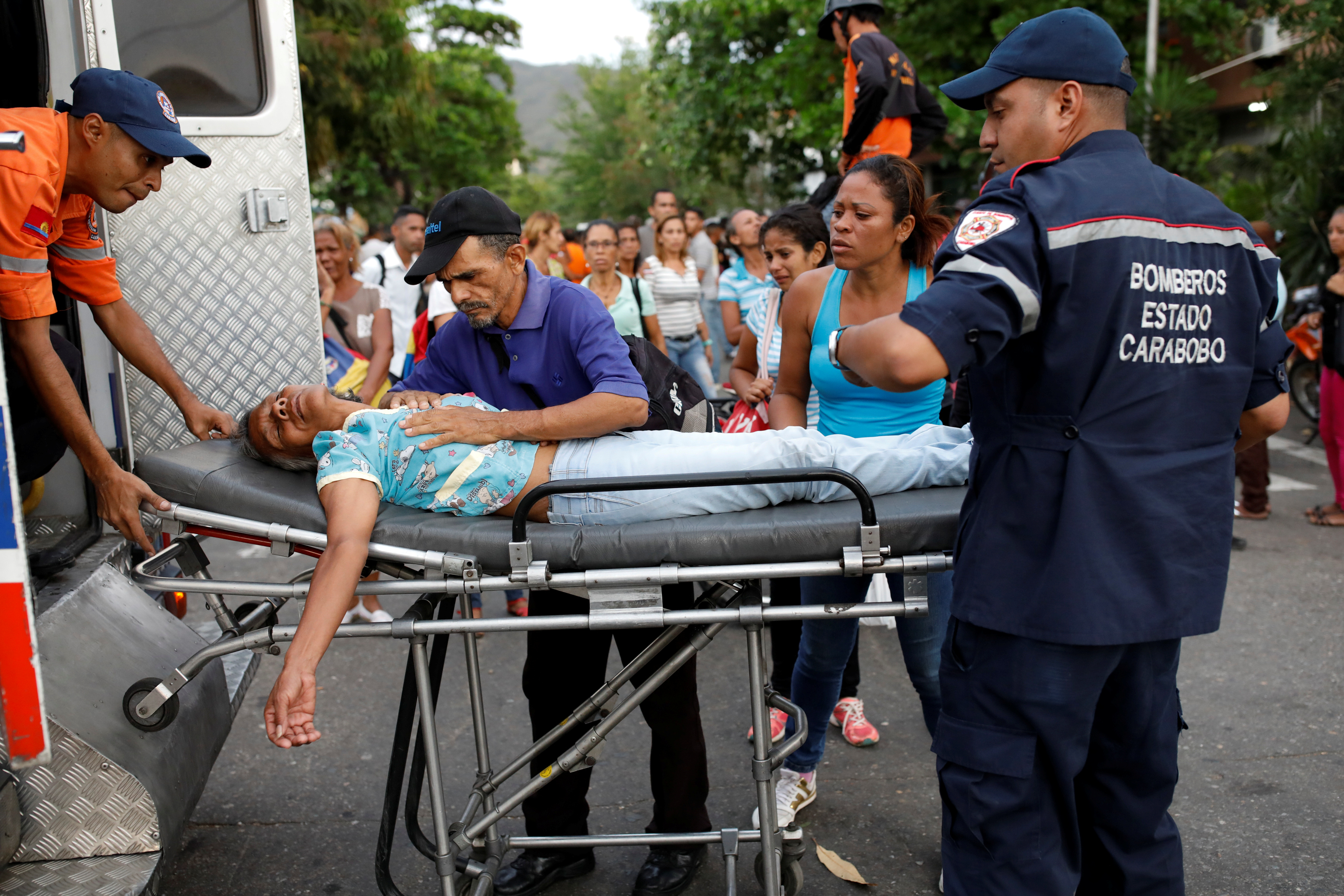 Paramedics help a woman who fainted outside the lockup where a fire occurred in Valencia, Venezuela on March 28, 2018. (Carlos Garcia Rawlins—Reuters)