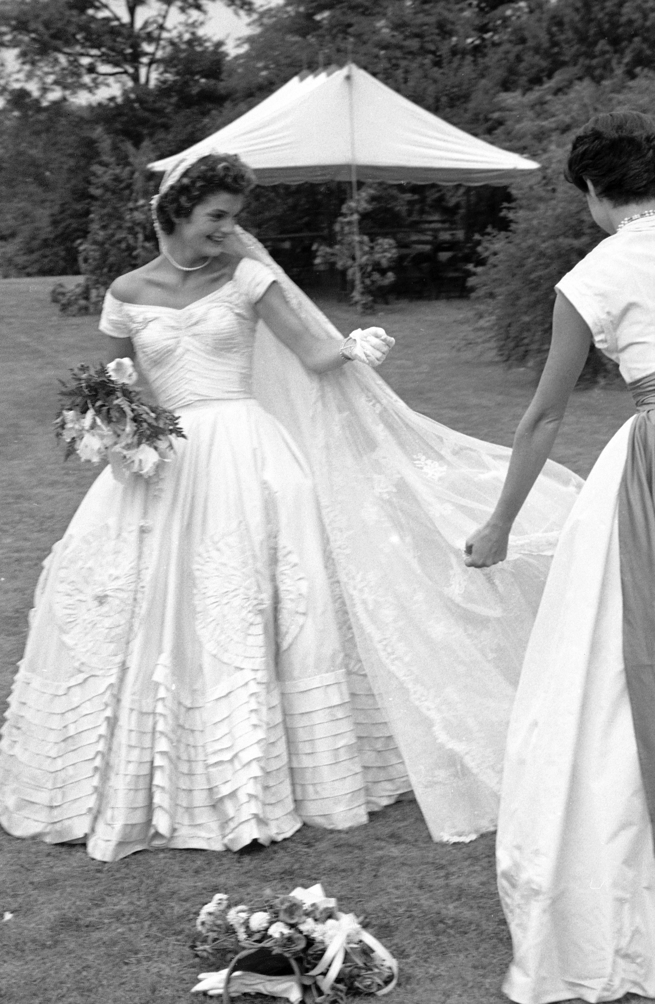 Jacqueline Bouvier fixing veil of wedding dress outdoors at Hammersmith Farm on day of her marriage to Senator John F. Kennedy, September 12, 1953.