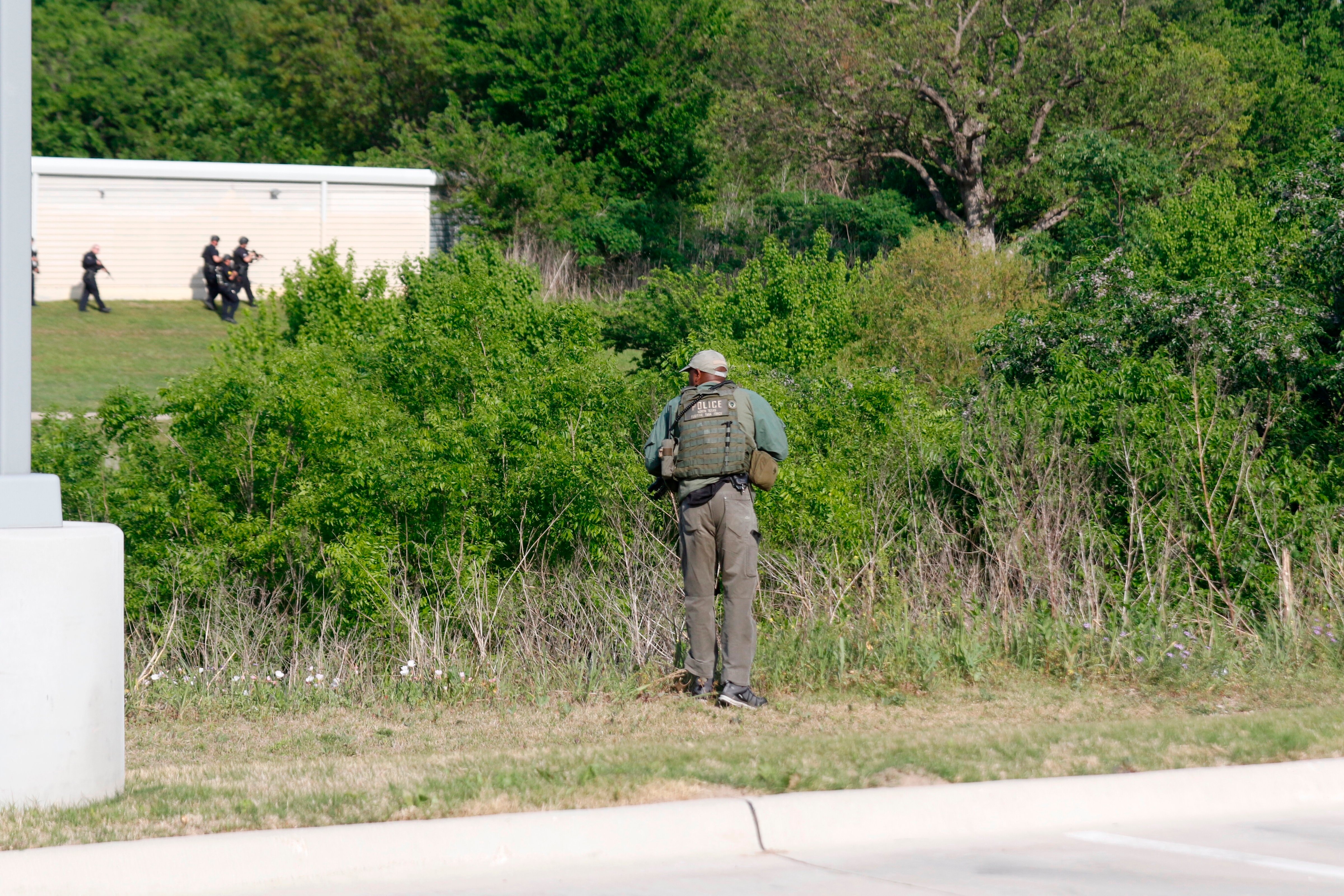 Dallas Police look for a suspect in the shooting of two police officers and a civilian Tuesday, April, 24,2018. Police are near ExtraSpace Storage, south of The Home Depot. Officer in the foreground is behind the Key-Whitman Eye Center on Central Expressway. (Ron Baselice/The Dallas Morning News via AP) (Ron Baselice—AP)