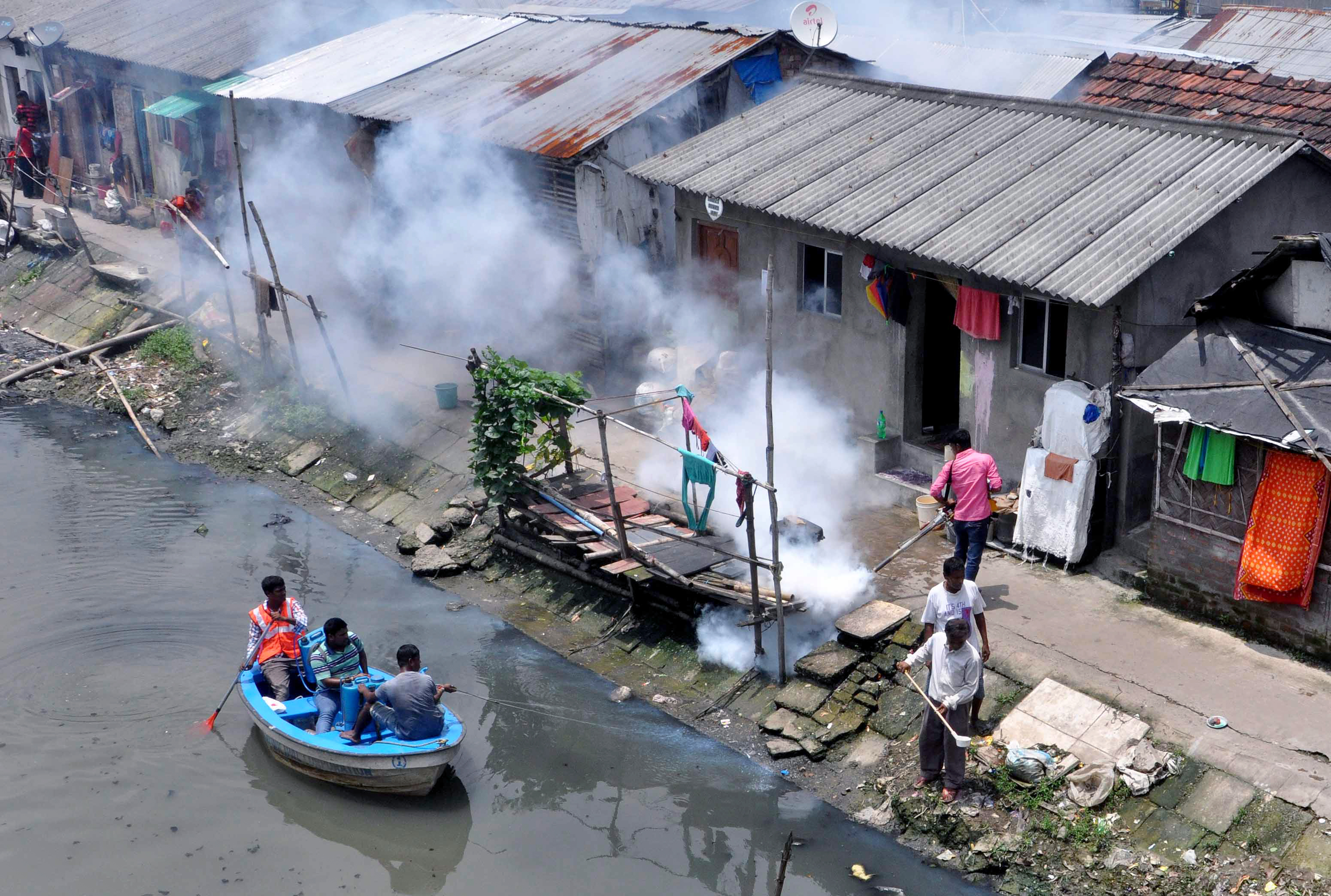 Municipal workers spray chemicals in canal and other worker fumigate slum area to kill mosquito in Kolkata. and malaria on August 9, 2017 in Kolkata. (Saikat Paul—Pacific Press/LightRocket/Getty Images)