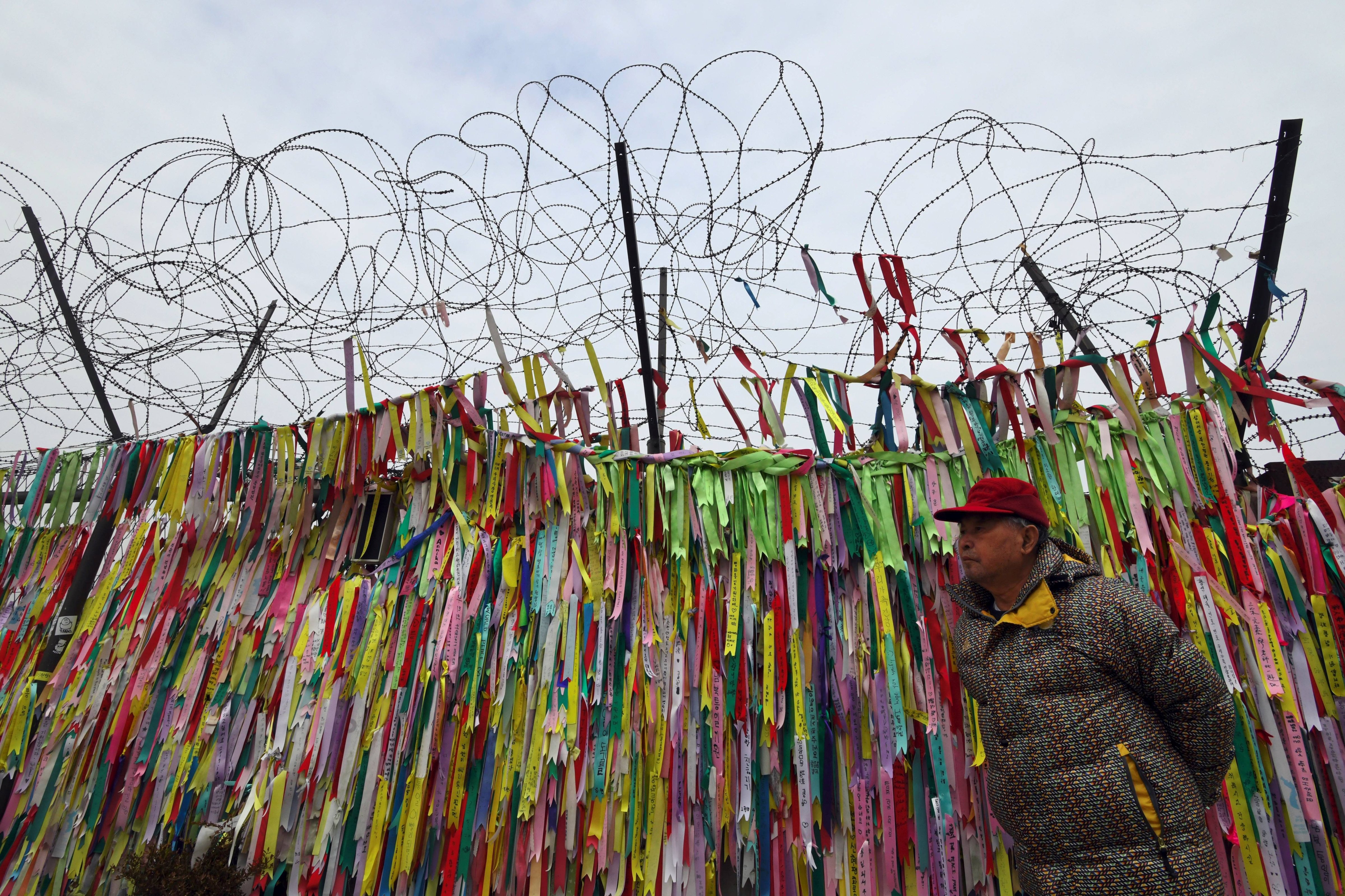 A man walks past a military fence covered with ribbons calling for peace and reunification at the Imjingak peace park near the Demilitarized Zone (DMZ) dividing the two Koreas at the border city of Paju on Jan. 8, 2018. (Jung Yeon-Je—AFP/Getty Images)