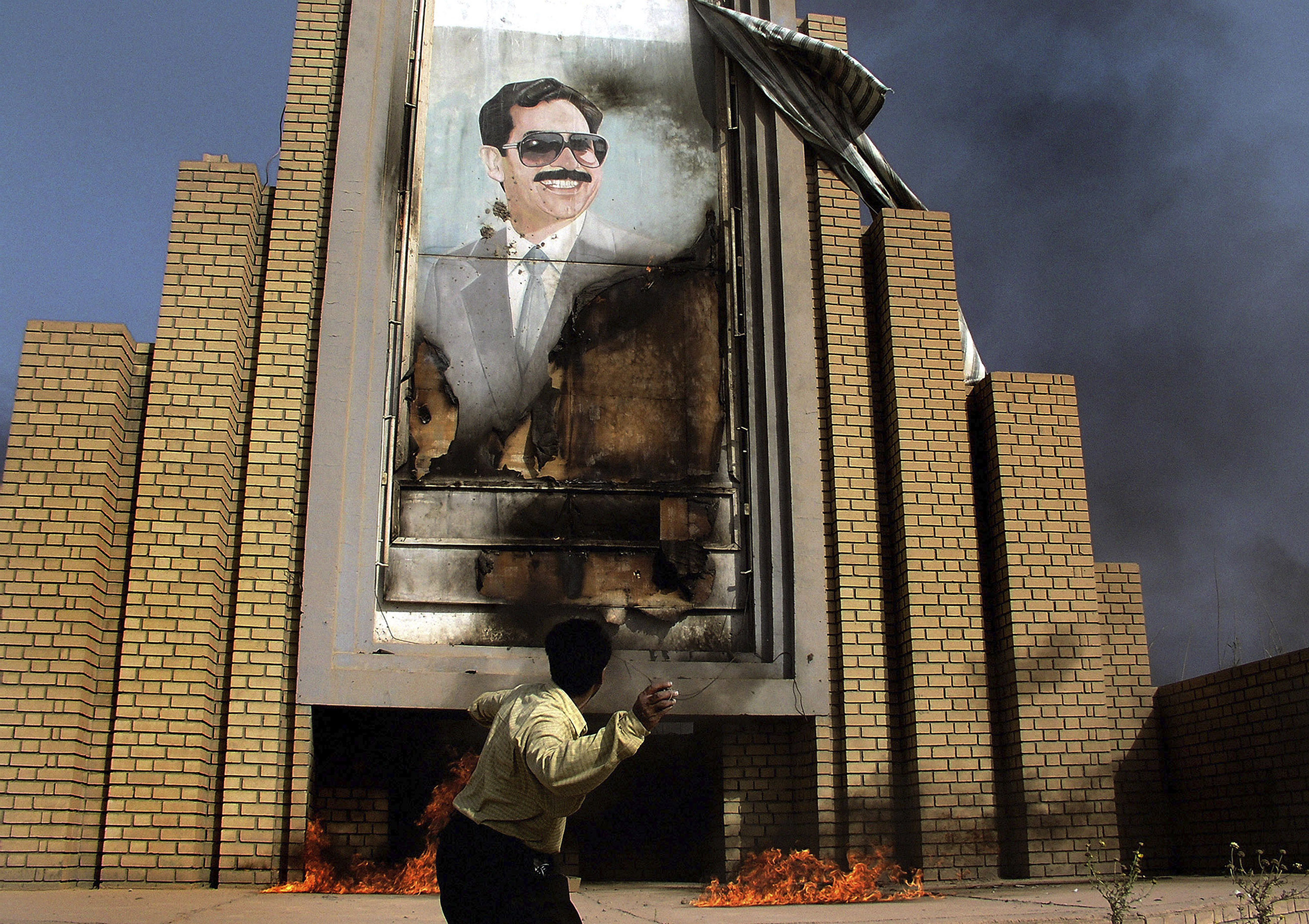 People burn and throw stones at a poster of Saddam Hussein in Baghdad, Iraq, on April 10, 2003. (Alex Majoli—Magnum Photos)