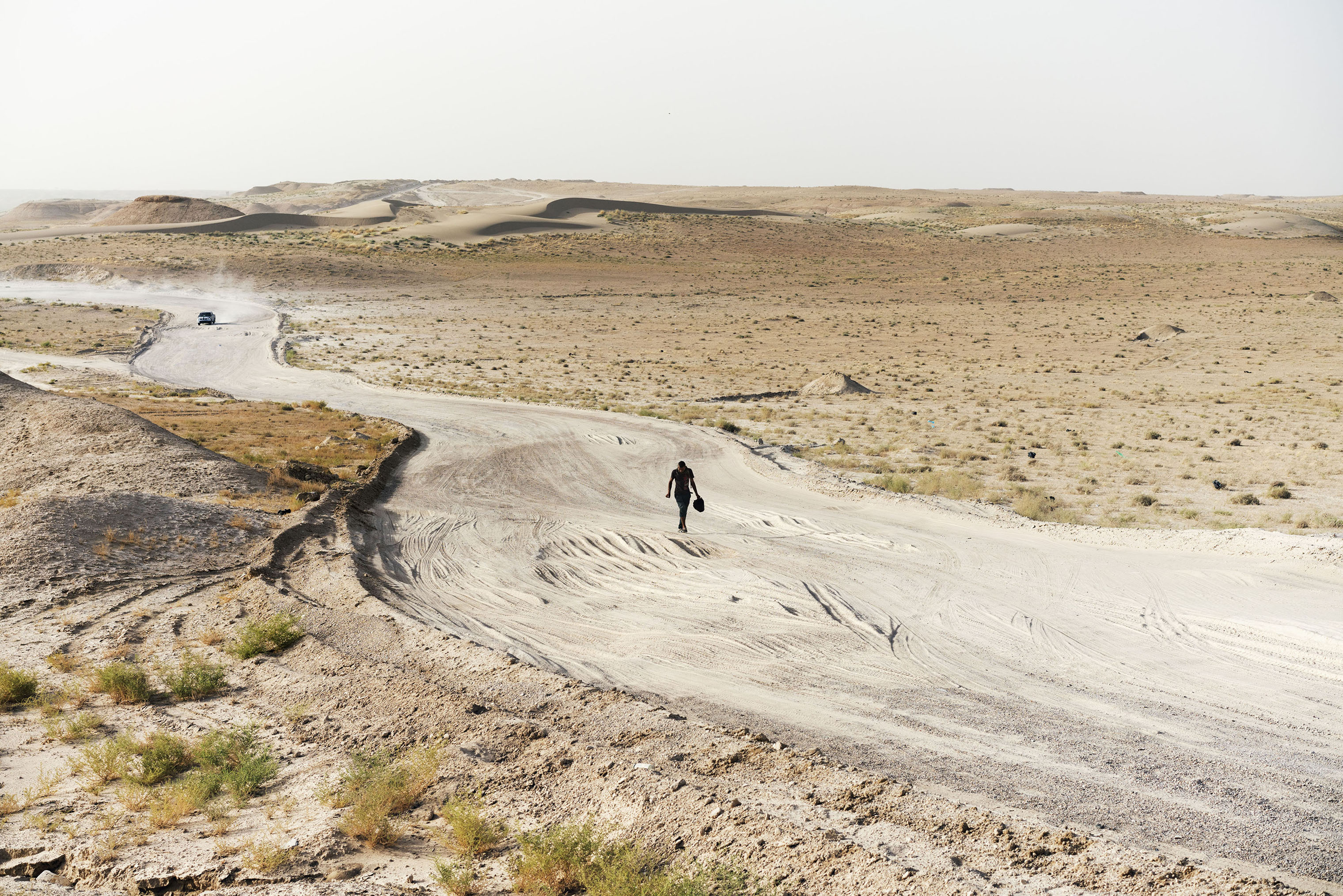 A man walks along a desert road near the town of Khalidiyah, in Iraq's Anbar Province, on July 12, 2016. The man, a native of Ramadi, was displaced when ISIS arrived in the city, and now lives with his family in a camp in the nearby town of Habbaniyah. Every day, he walks from Habbaniyah to Ramadi, where he works as a laborer clearing rubble from the war-torn streets. (Moises Saman—Magnum Photos)