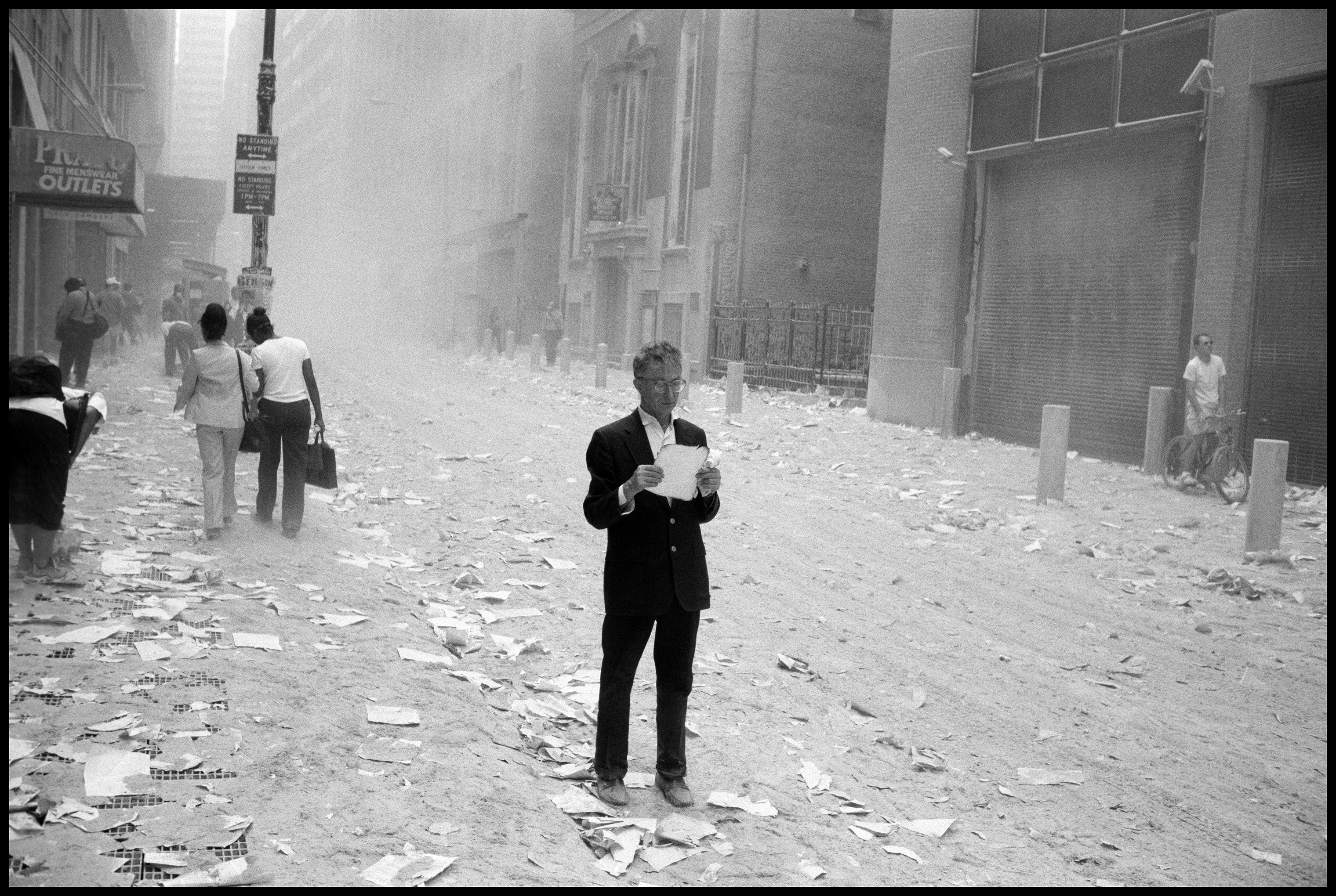 A man picks up a paper that was blown out of the towers after the attack of the World Trade Center on Sept. 11, 2001. (Larry Towell—Magnum Photos)
