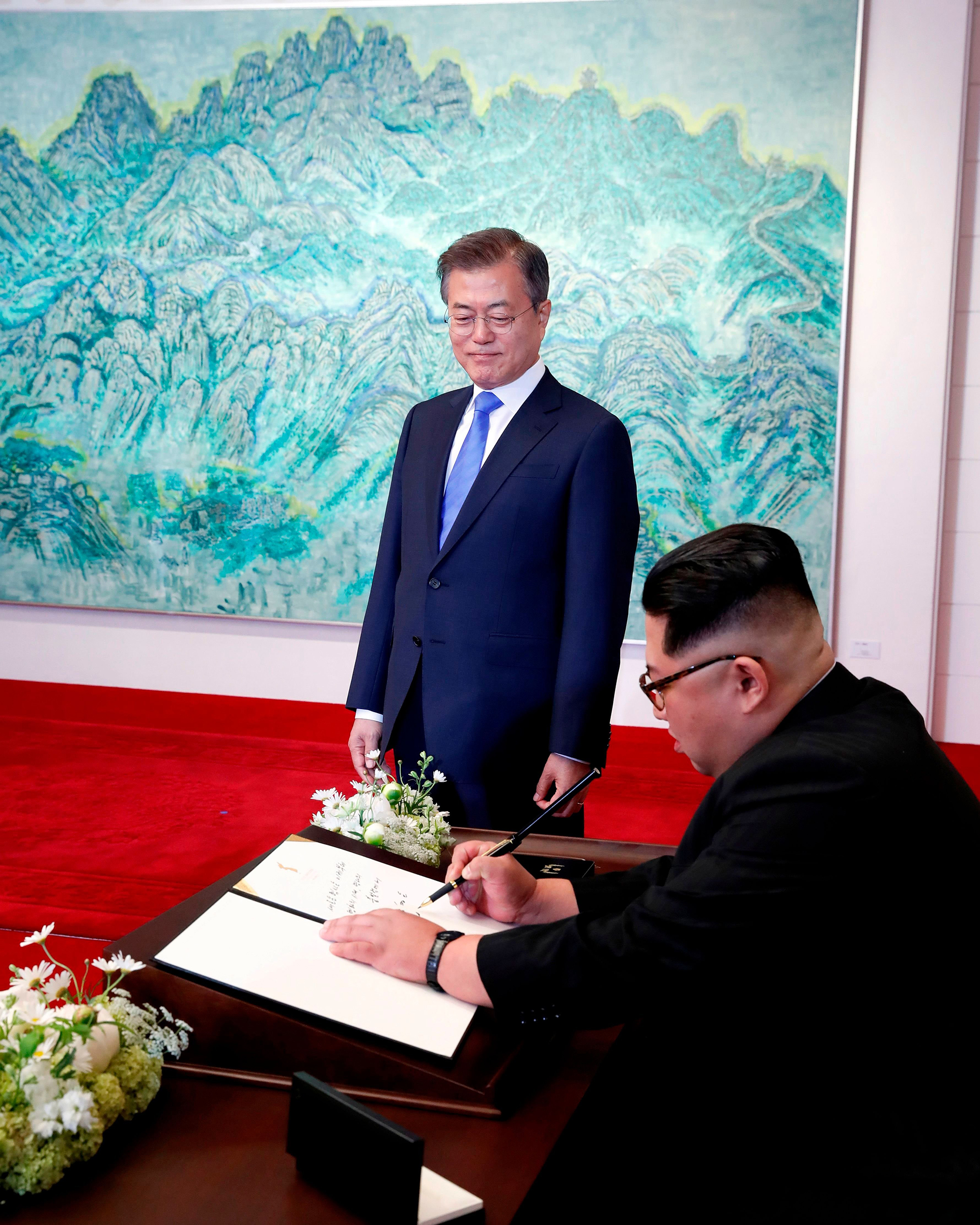 North Korean leader Kim Jong-Un (R) signs his name in the visitors' book before an inter-Korean summit with South Korean President Moon Jae-In at the Peace House at the south side of the truce village of Panmunjom in the demilitarized zone (Aflo—Shutterstock)