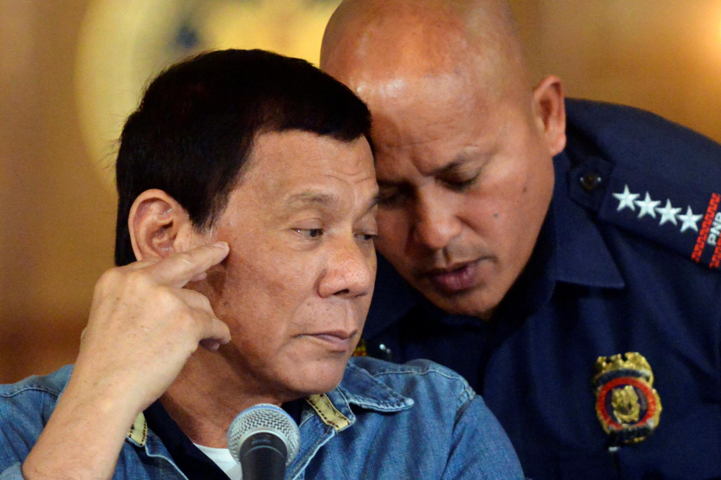 Philippine President Rodrigo Duterte listens as PNP Director General Ronald Dela Rosa whispers to him, during a late night news conference at the presidential palace in Manila
