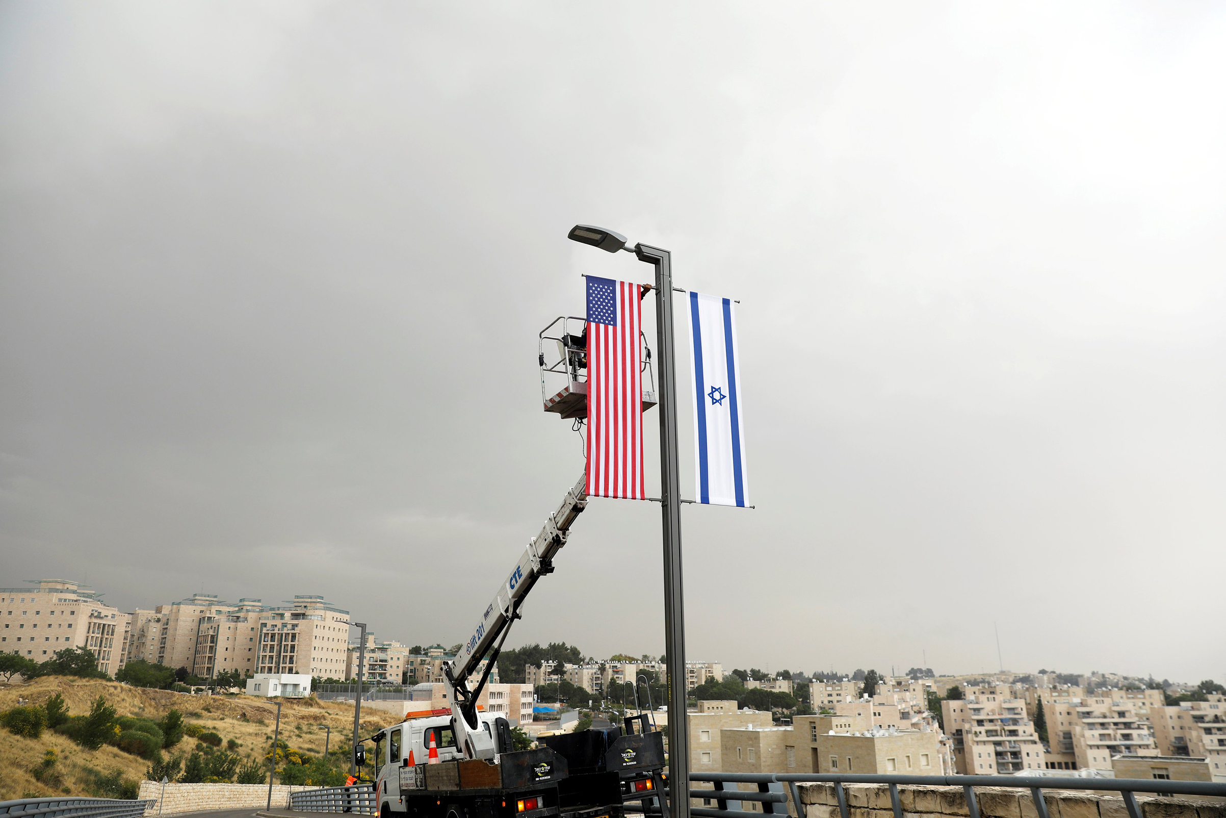 A worker on a crane hangs a U.S. flag alongside an Israeli flag, next to the entrance to the U.S. consulate in Jerusalem, on May 7, 2018. (Ronen Zvulun—Reuters)