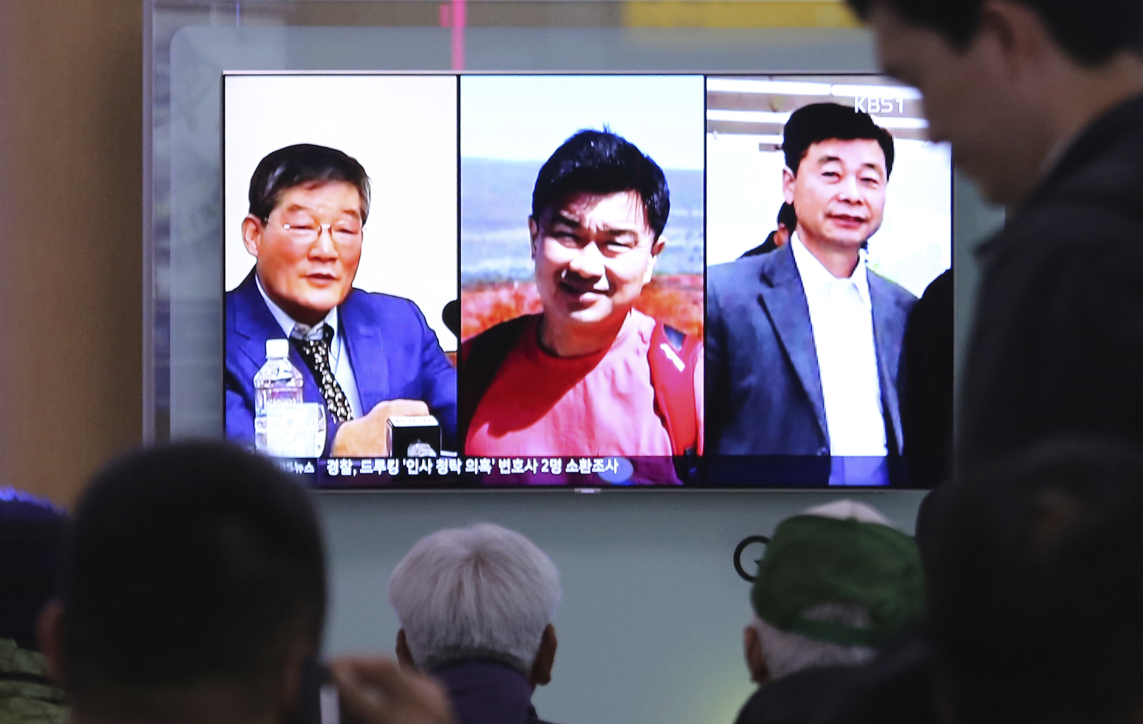 FILE - In this May 3, 2018 photo, people watch a TV news report on screen, showing portraits of three Americans, Kim Dong Chul, left, Tony Kim and Kim Hak Song, right, detained in the North Korea, at the Seoul Railway Station in Seoul, South Korea. President Donald Trump says Secretary of State Mike Pompeo is on his way back from North Korea with three American detainees, saying they 