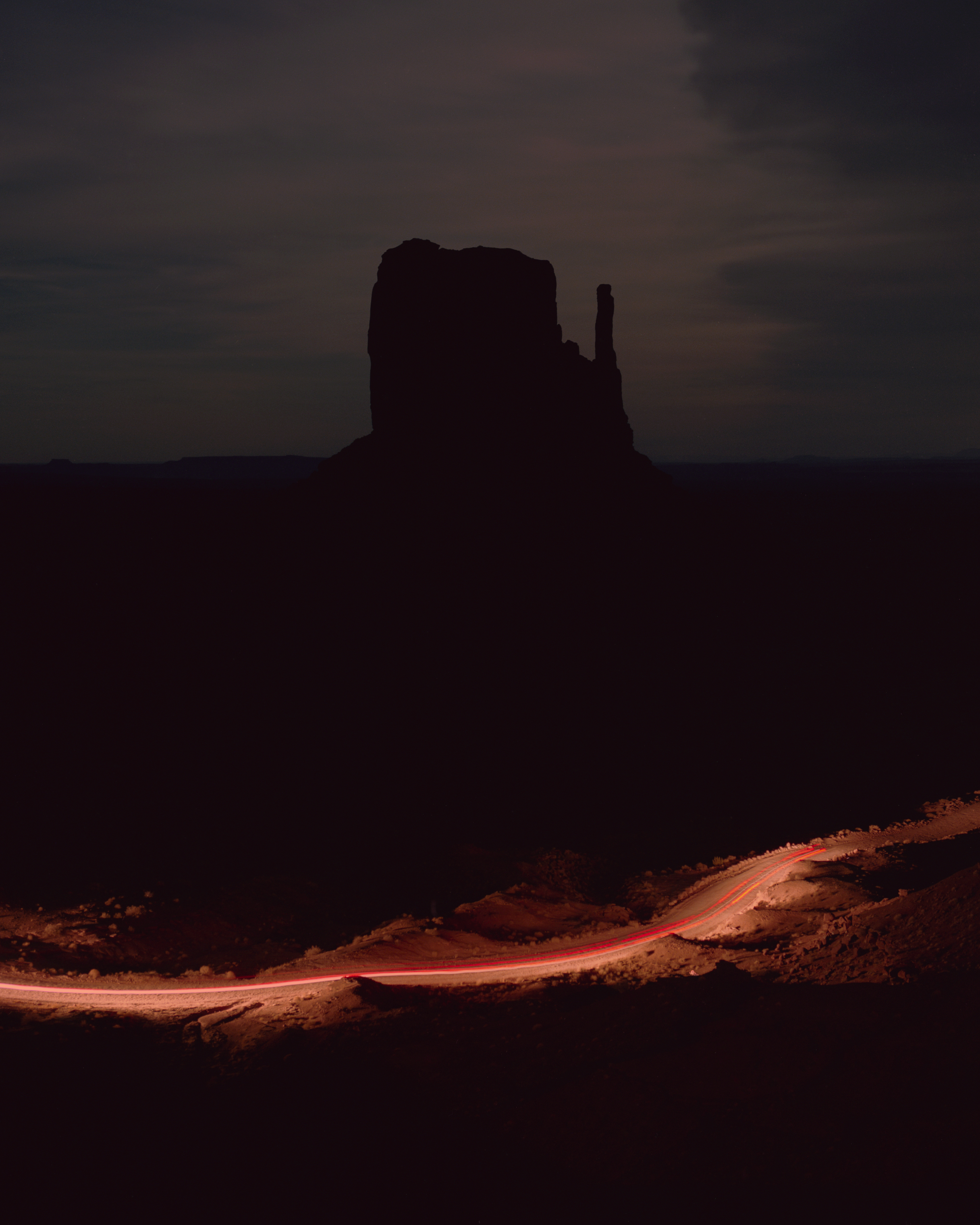 A car illuminates a dirt roadway leading into Monument Valley. (Ryan Shorosky for TIME)